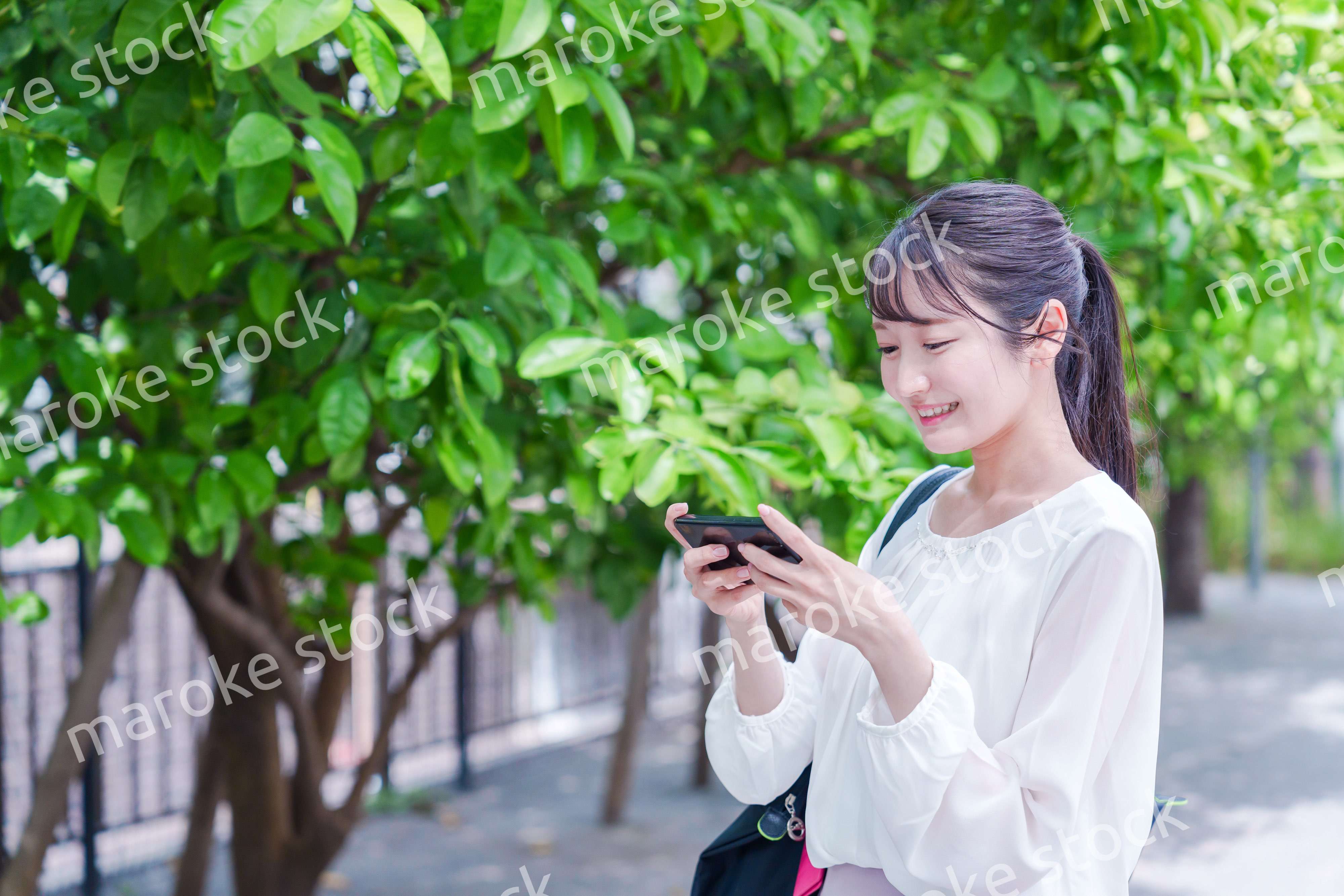 笑顔でスマホを見ながら歩く若い女性