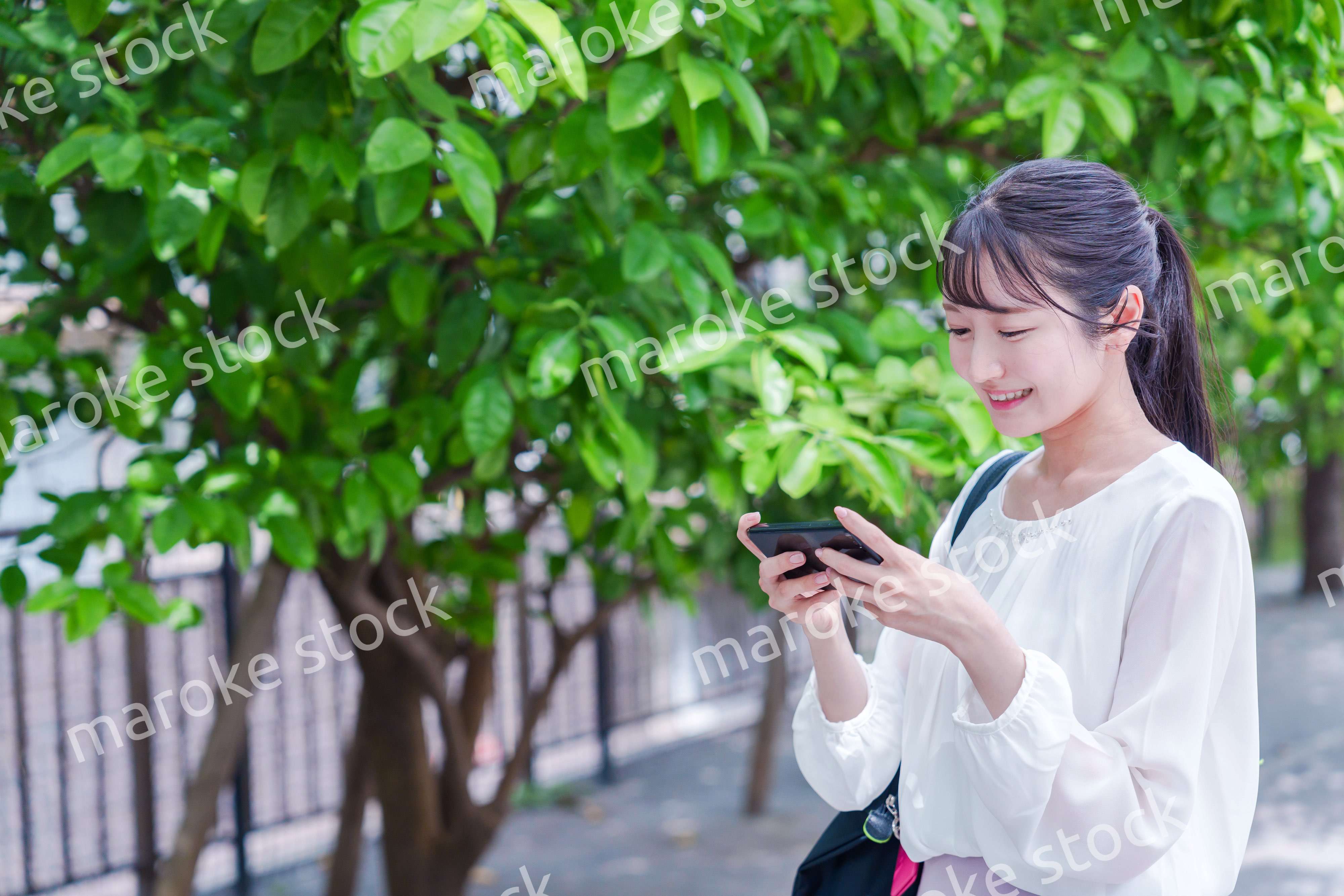 笑顔でスマホを見ながら歩く若い女性