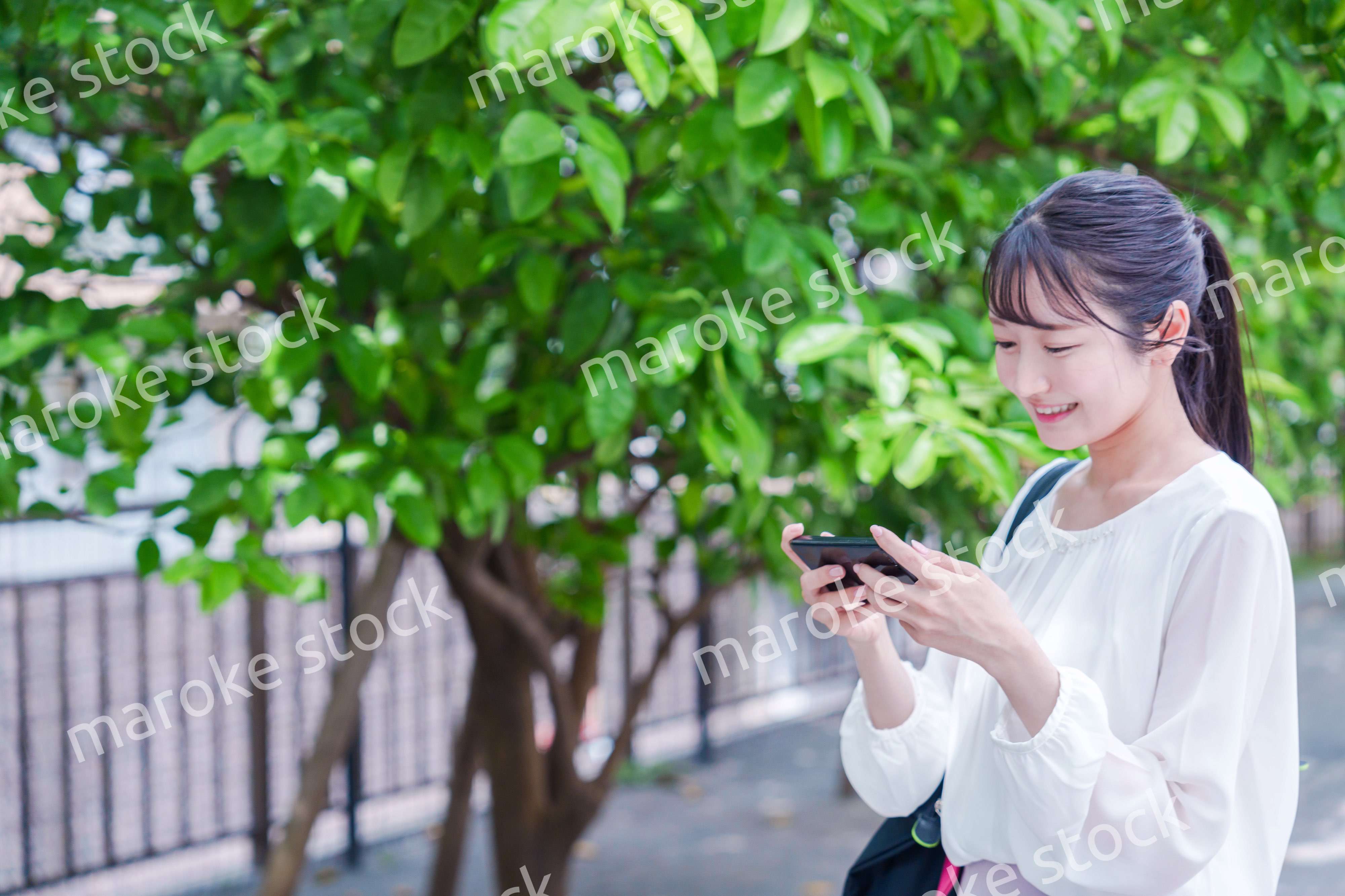 笑顔でスマホを見ながら歩く若い女性