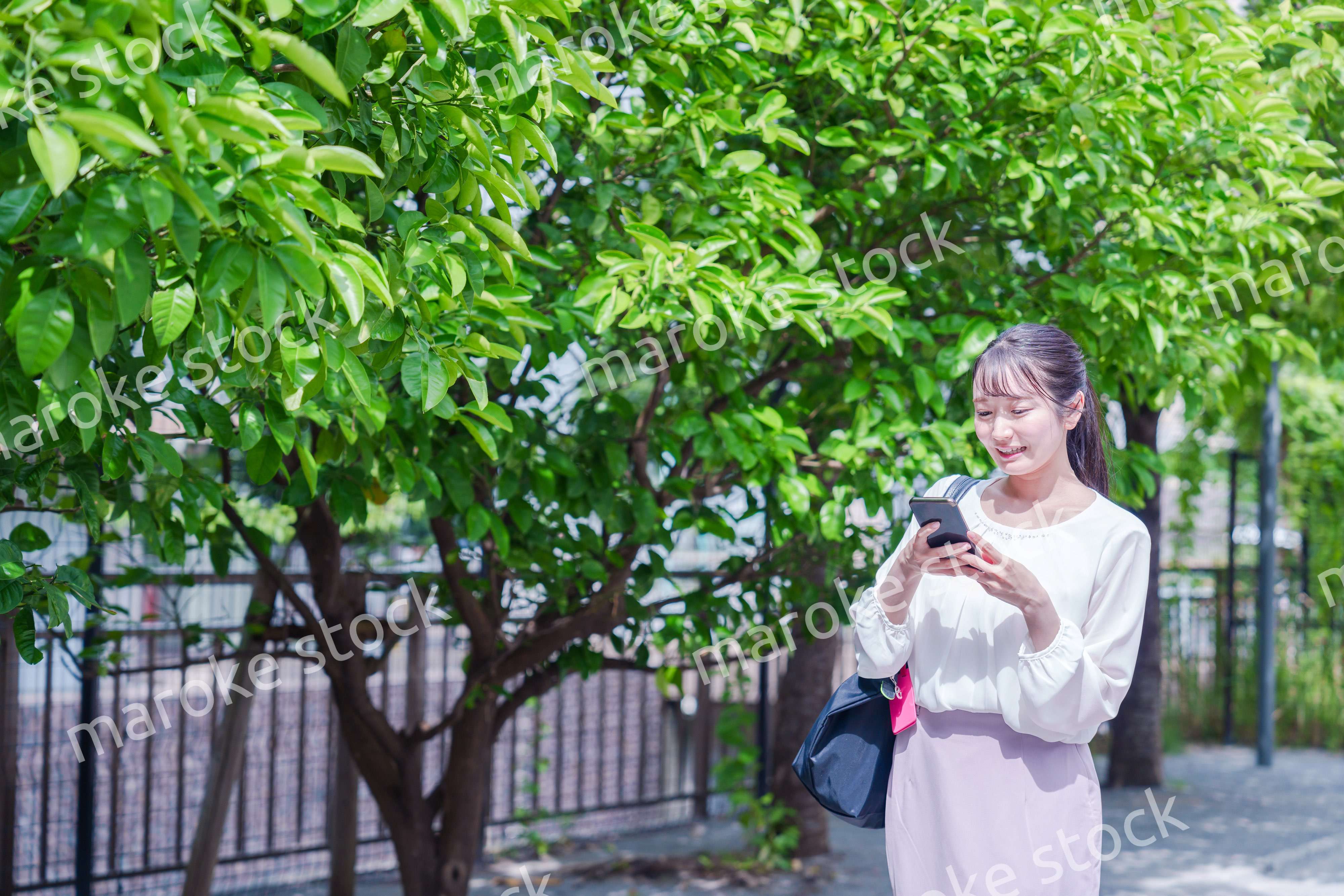 笑顔でスマホを見ながら歩く若い女性