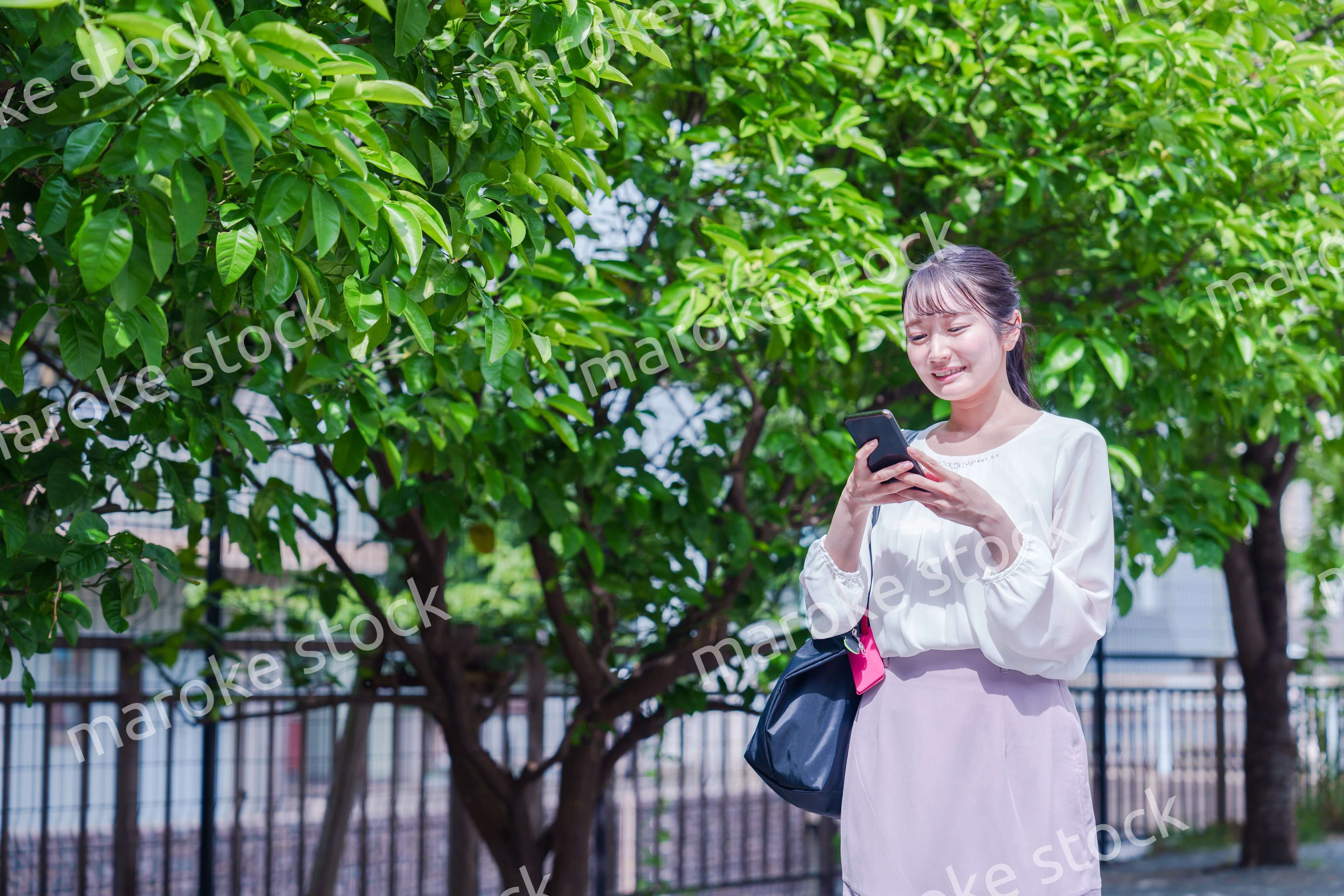 笑顔でスマホを見ながら歩く若い女性