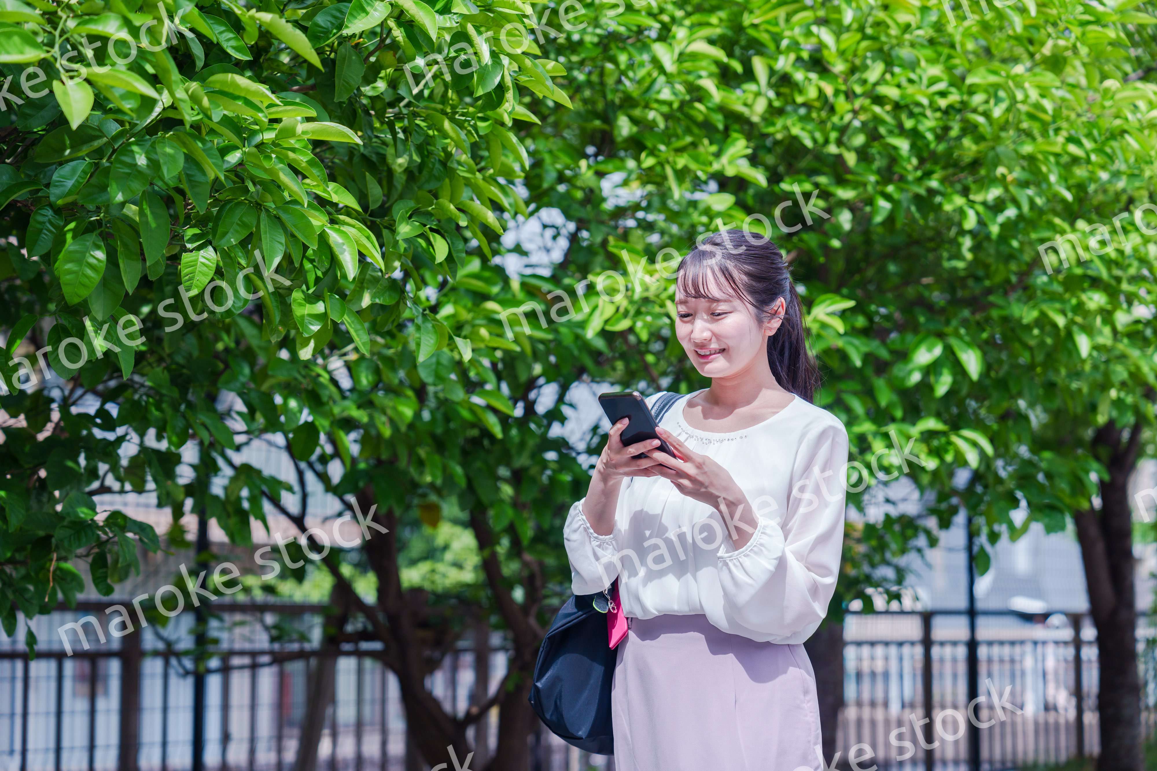 笑顔でスマホを見ながら歩く若い女性