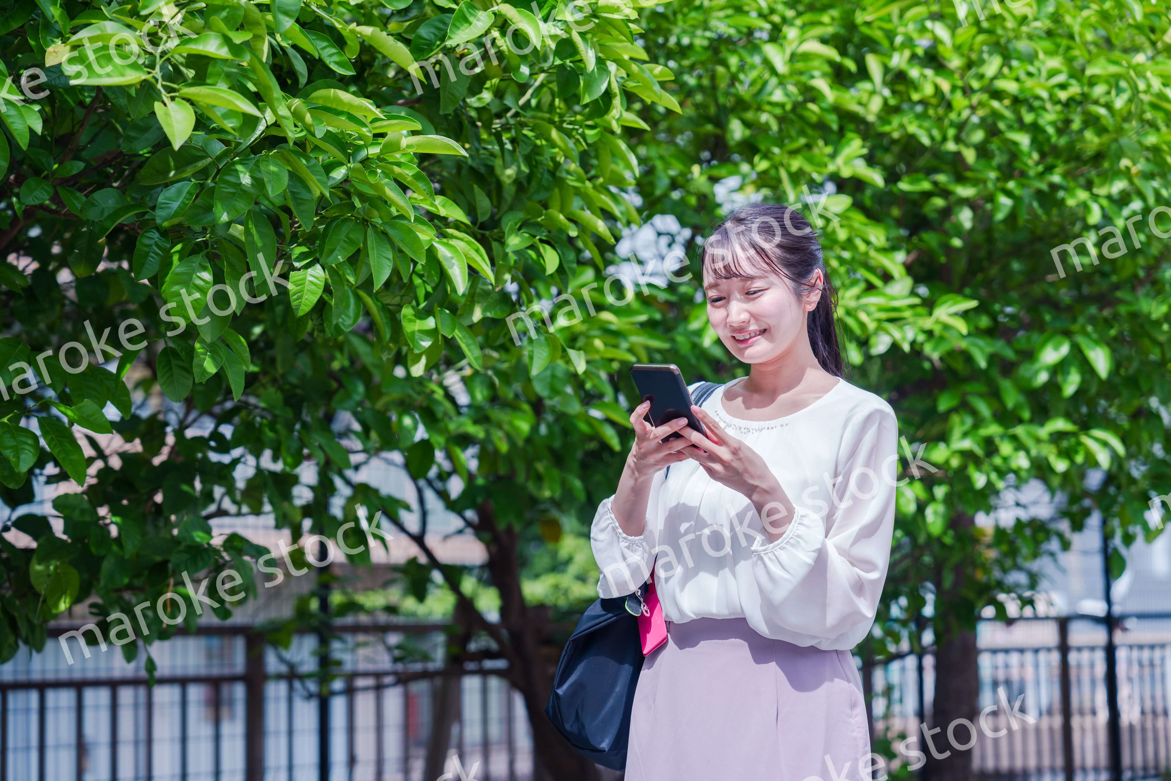 笑顔でスマホを見ながら歩く若い女性