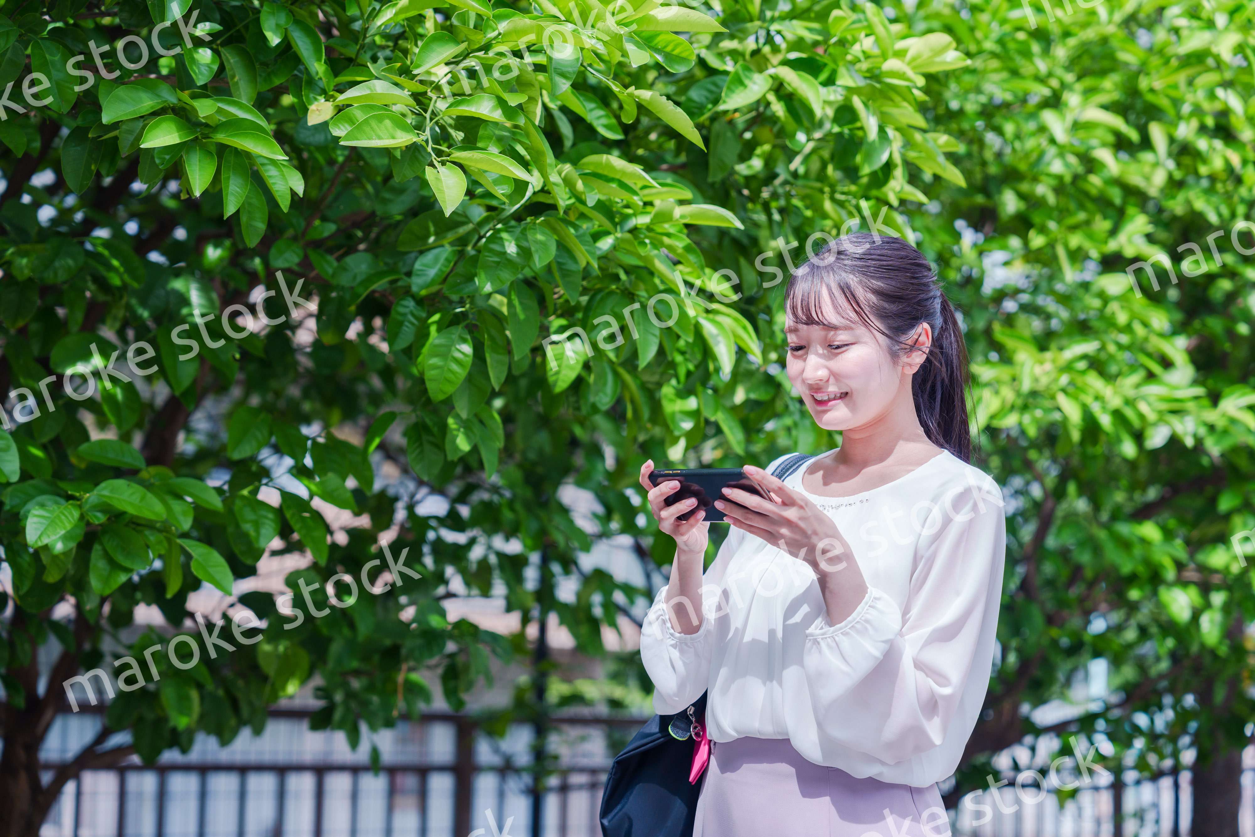 笑顔でスマホを見ながら歩く若い女性