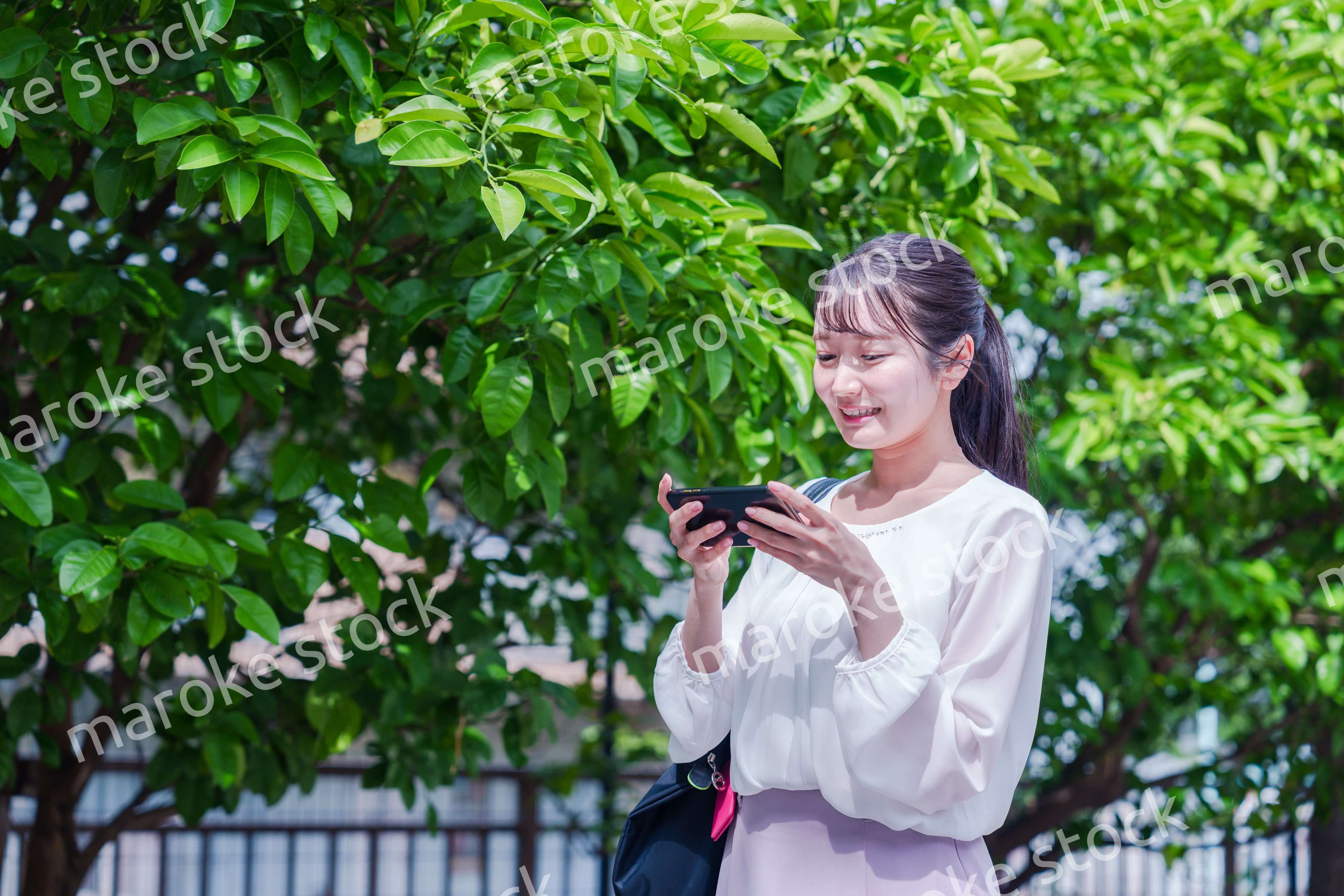 笑顔でスマホを見ながら歩く若い女性