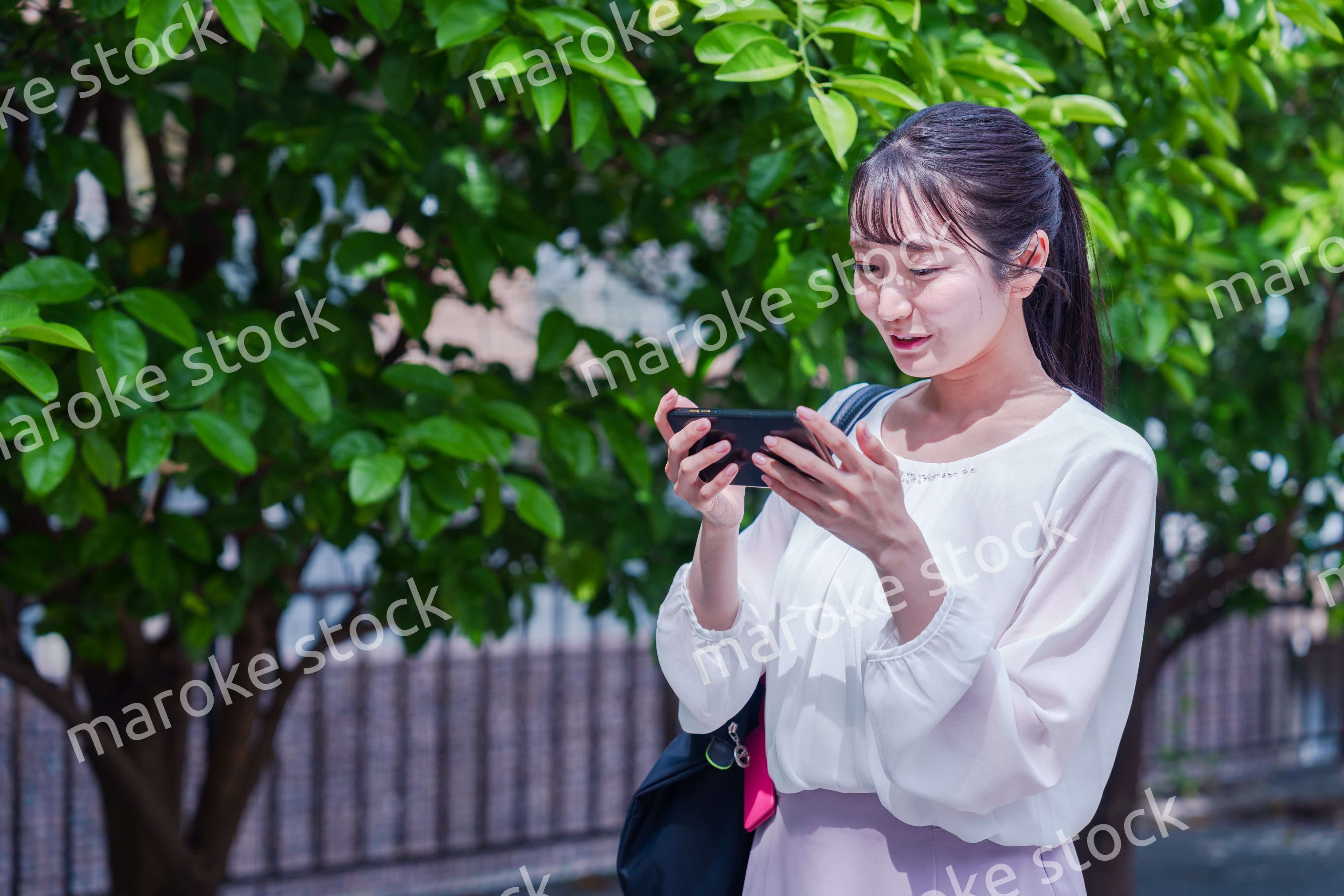 笑顔でスマホを見ながら歩く若い女性