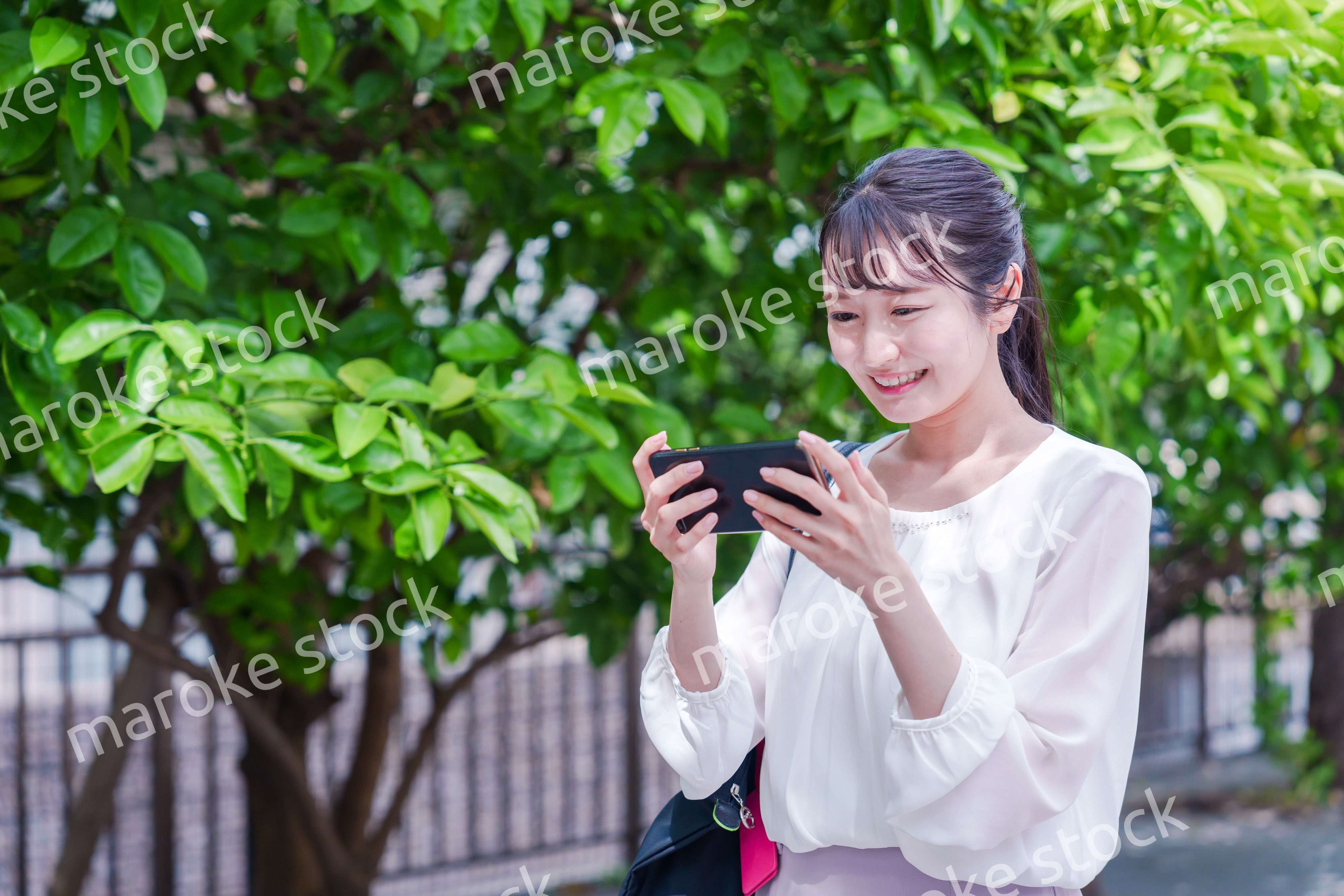 笑顔でスマホを見ながら歩く若い女性