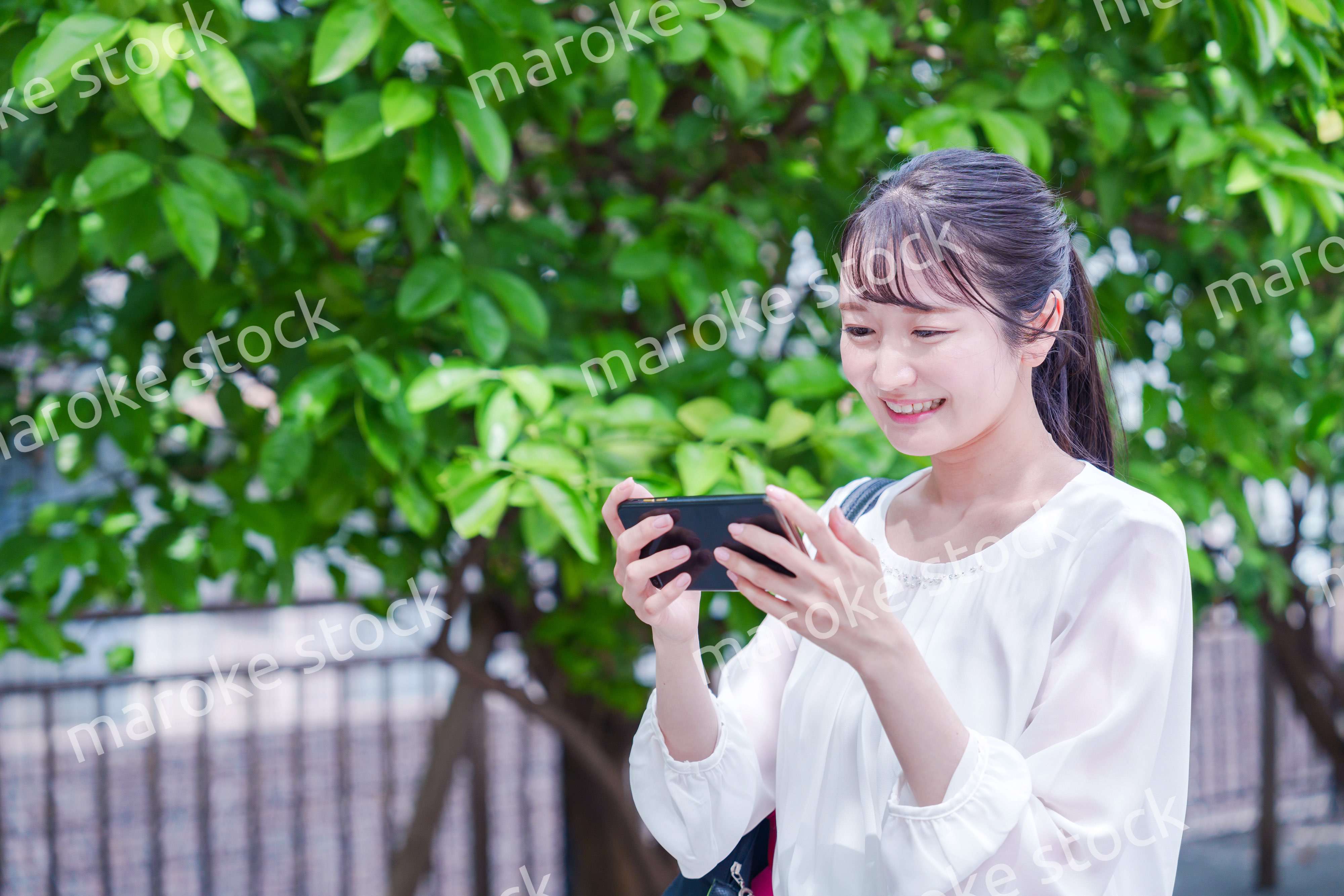 笑顔でスマホを見ながら歩く若い女性