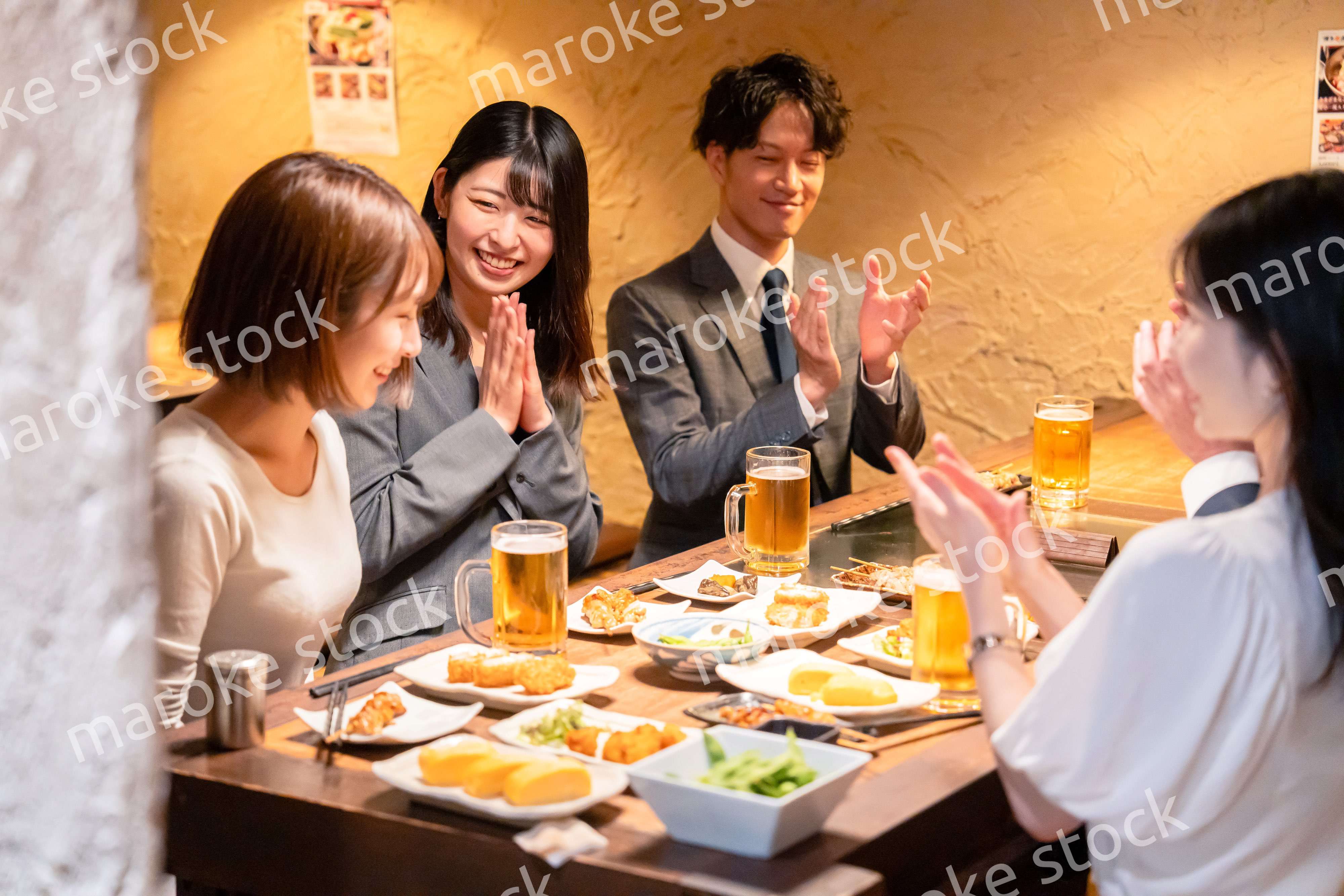 居酒屋で拍手をするビジネスパーソン