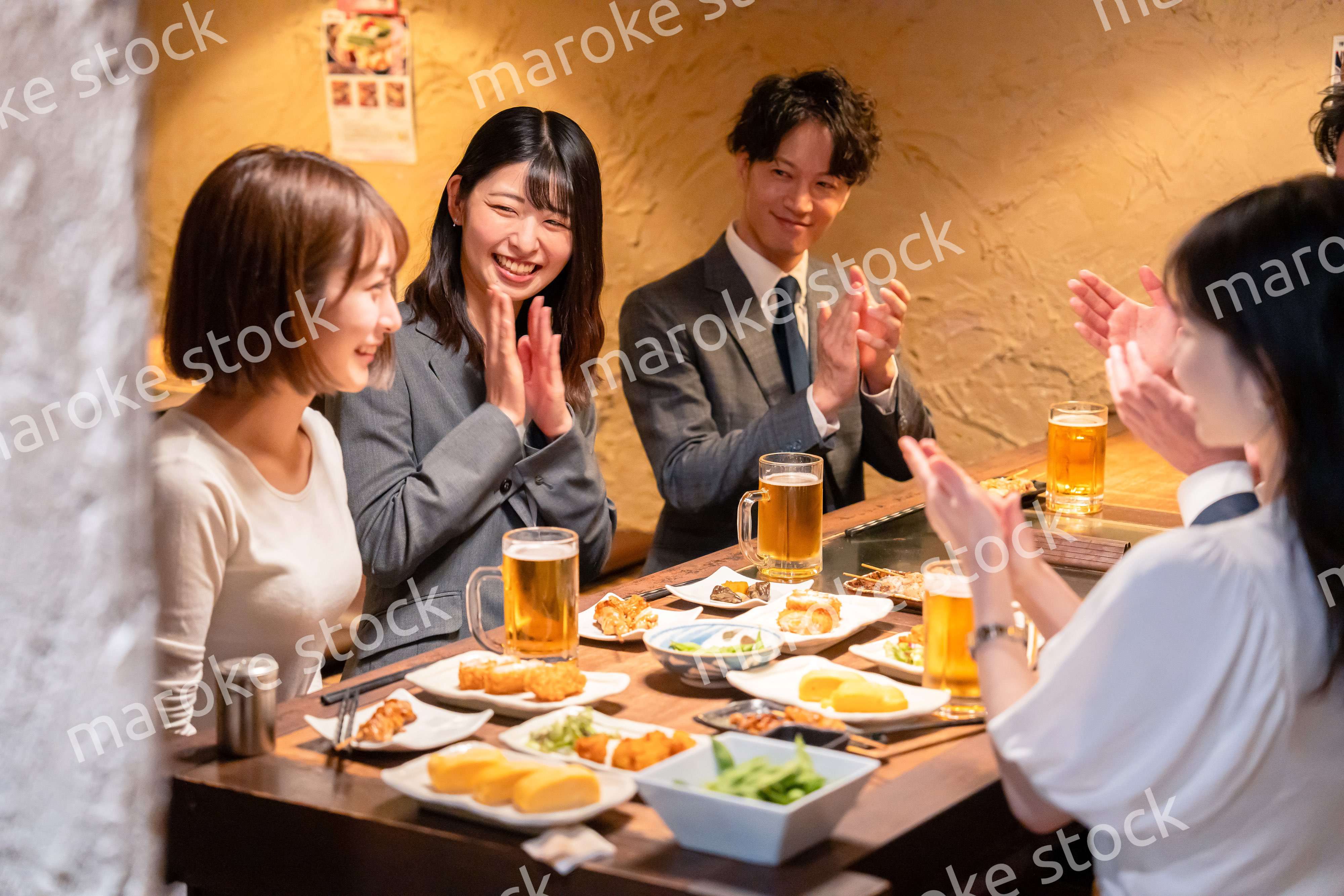 居酒屋で拍手をするビジネスパーソン