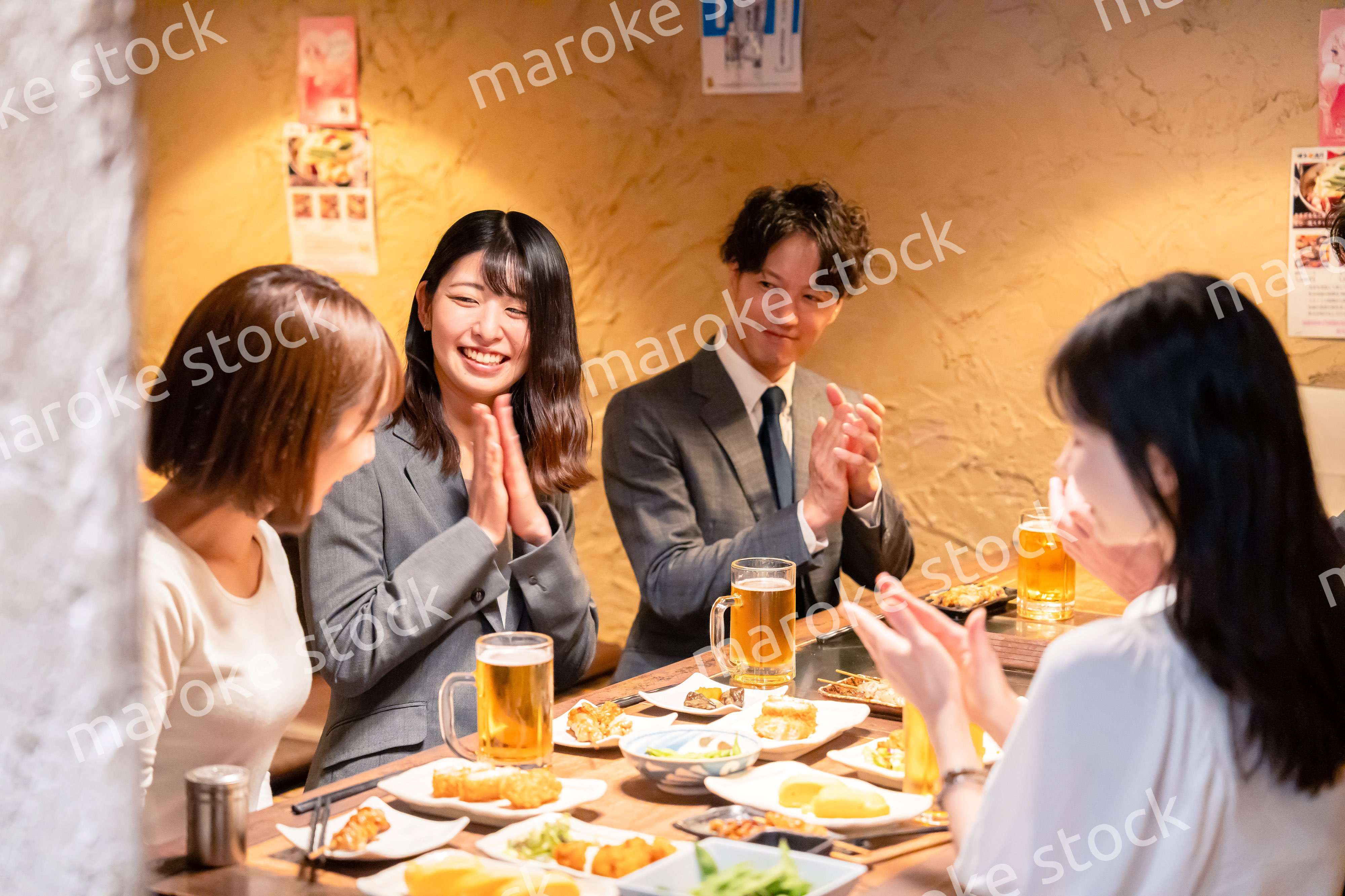 居酒屋で拍手をするビジネスパーソン