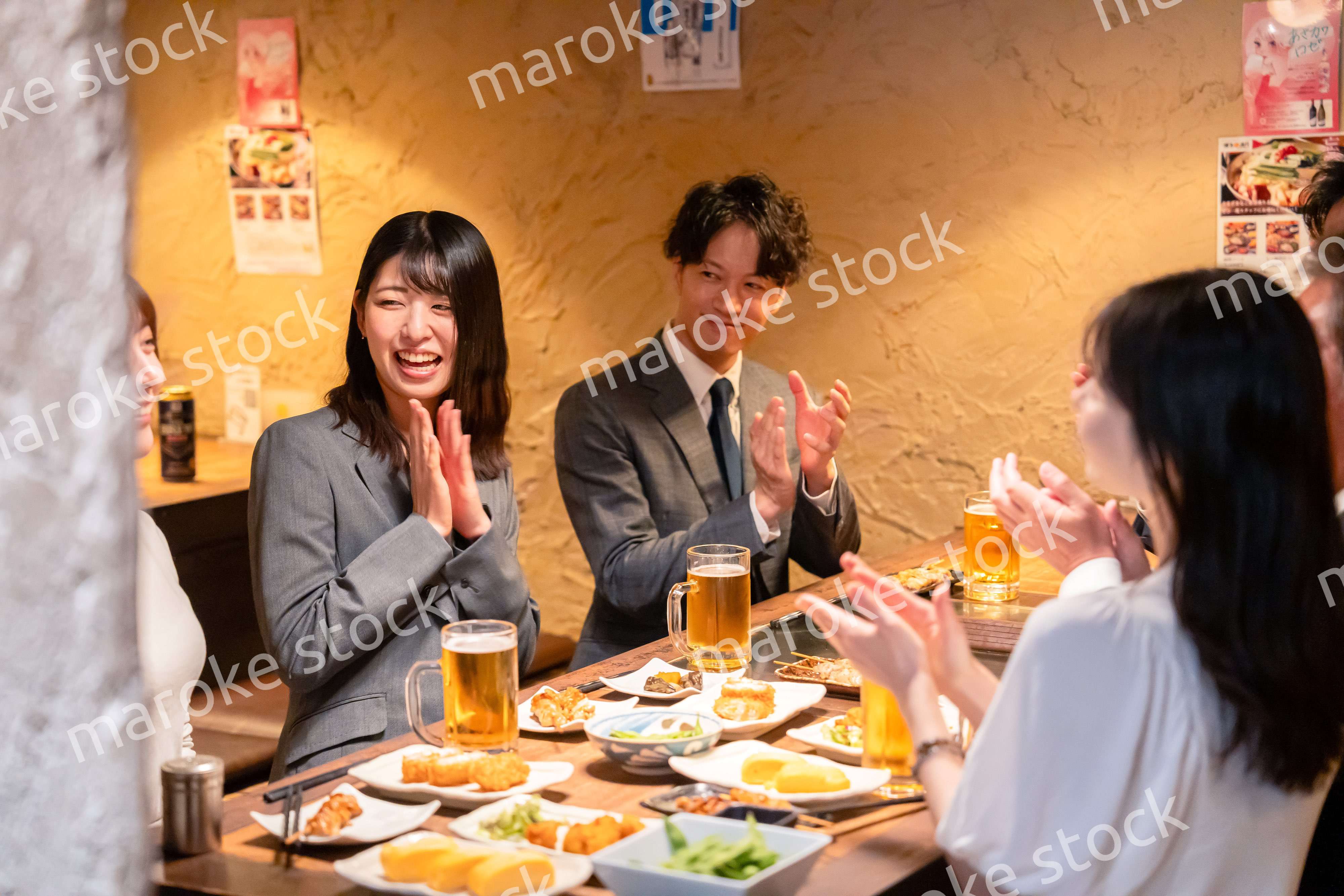 居酒屋で拍手をするビジネスパーソン