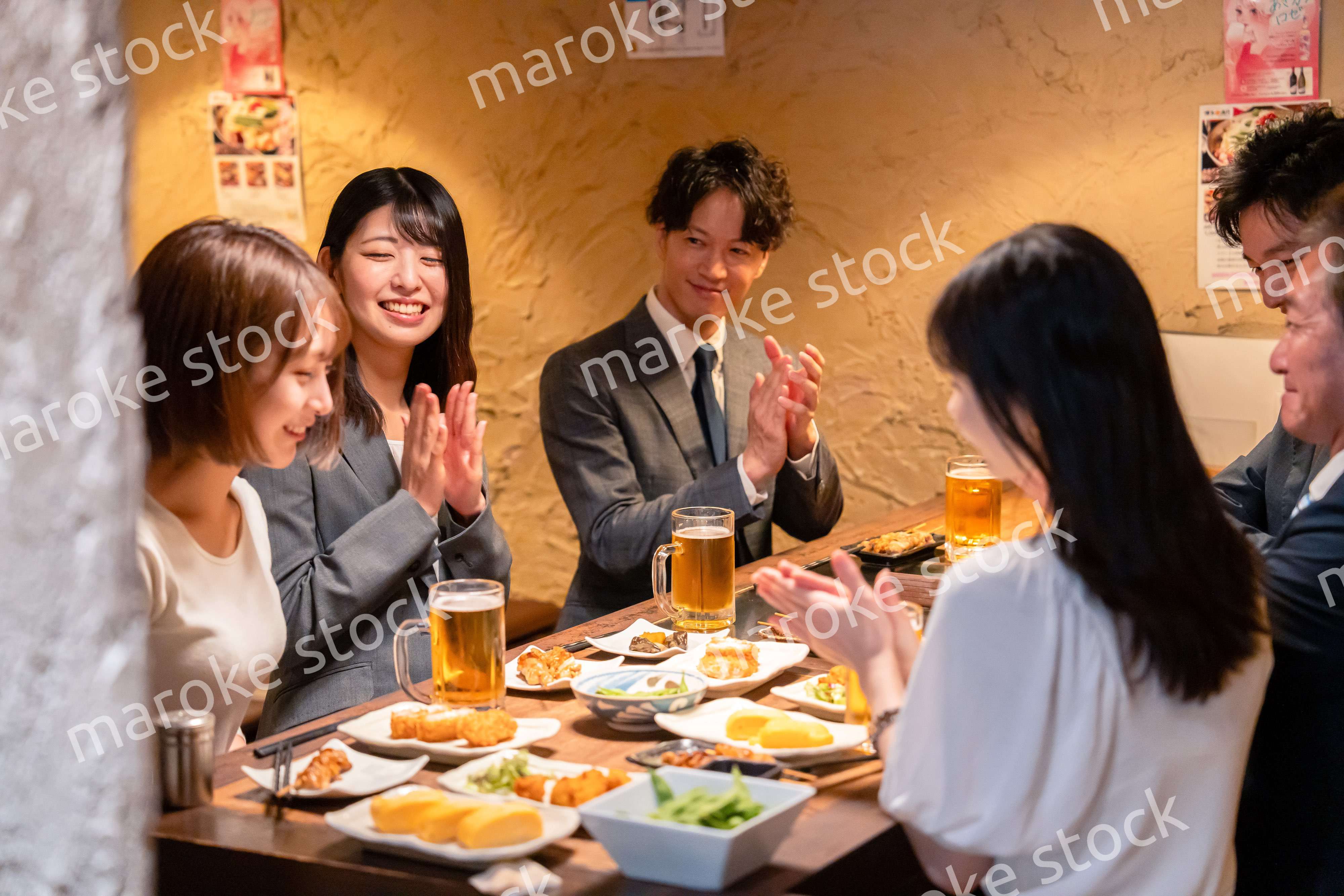 居酒屋で拍手をするビジネスパーソン