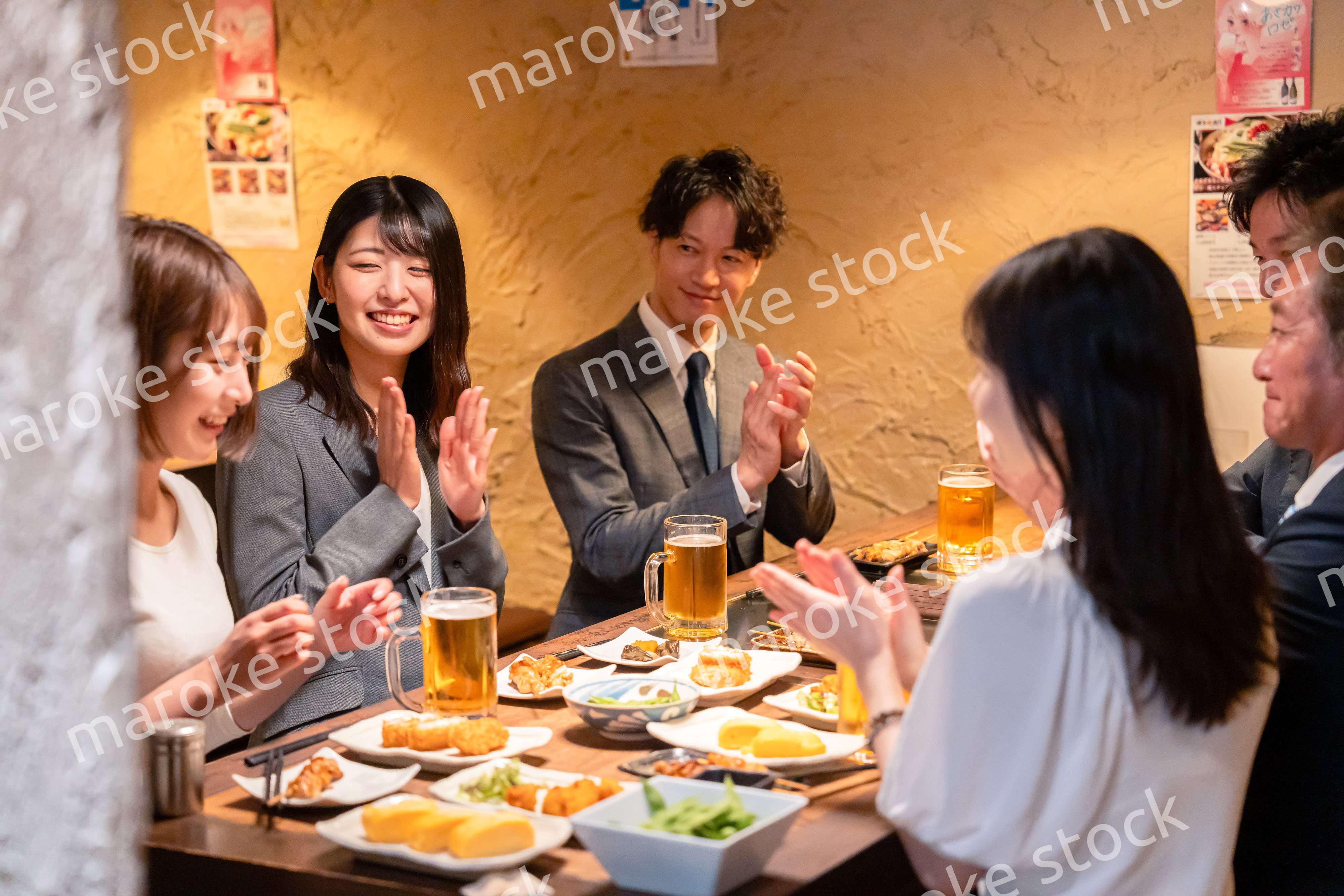 居酒屋で拍手をするビジネスパーソン