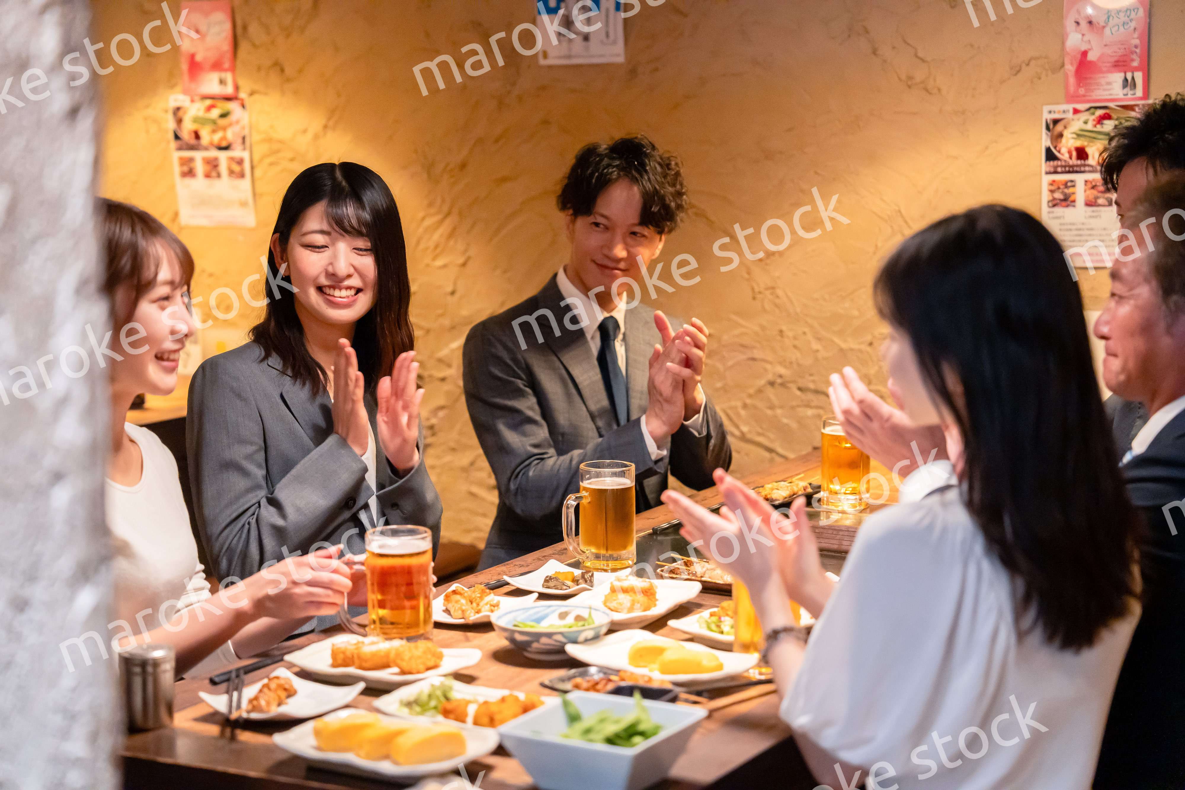 居酒屋で拍手をするビジネスパーソン