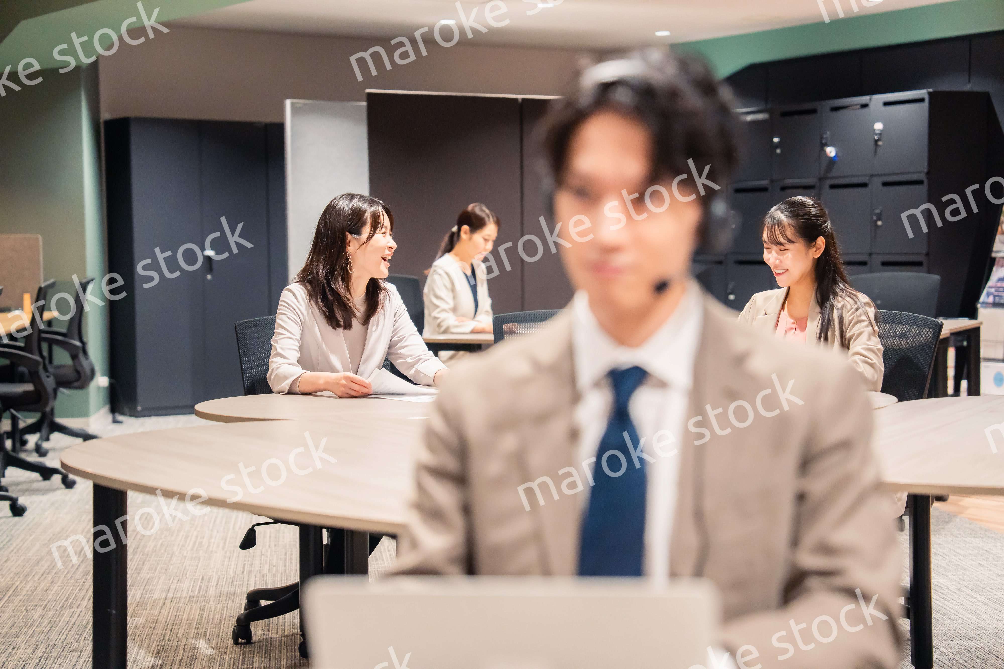 オフィスで楽しく話しながら働く女性