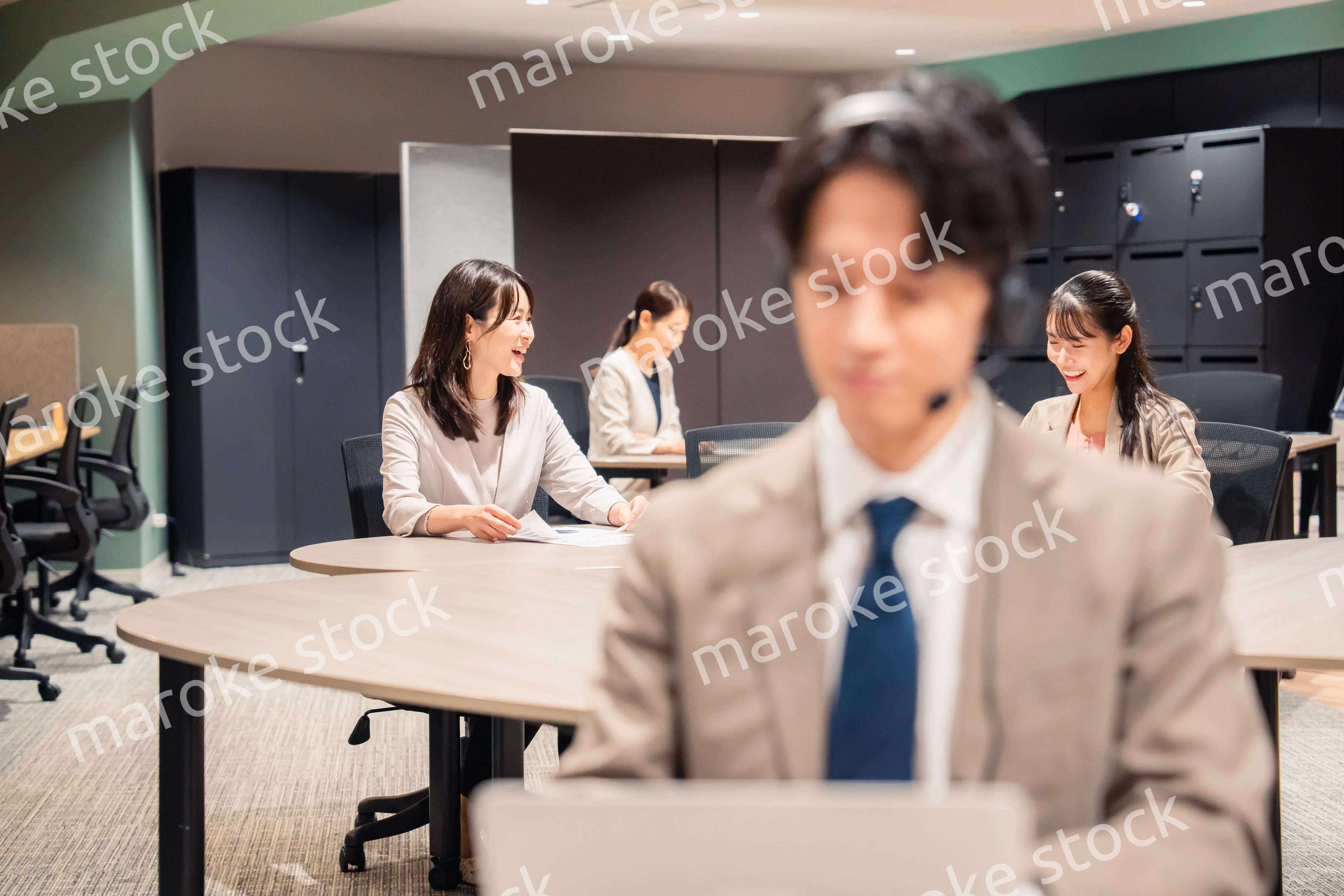 オフィスで楽しく話しながら働く女性