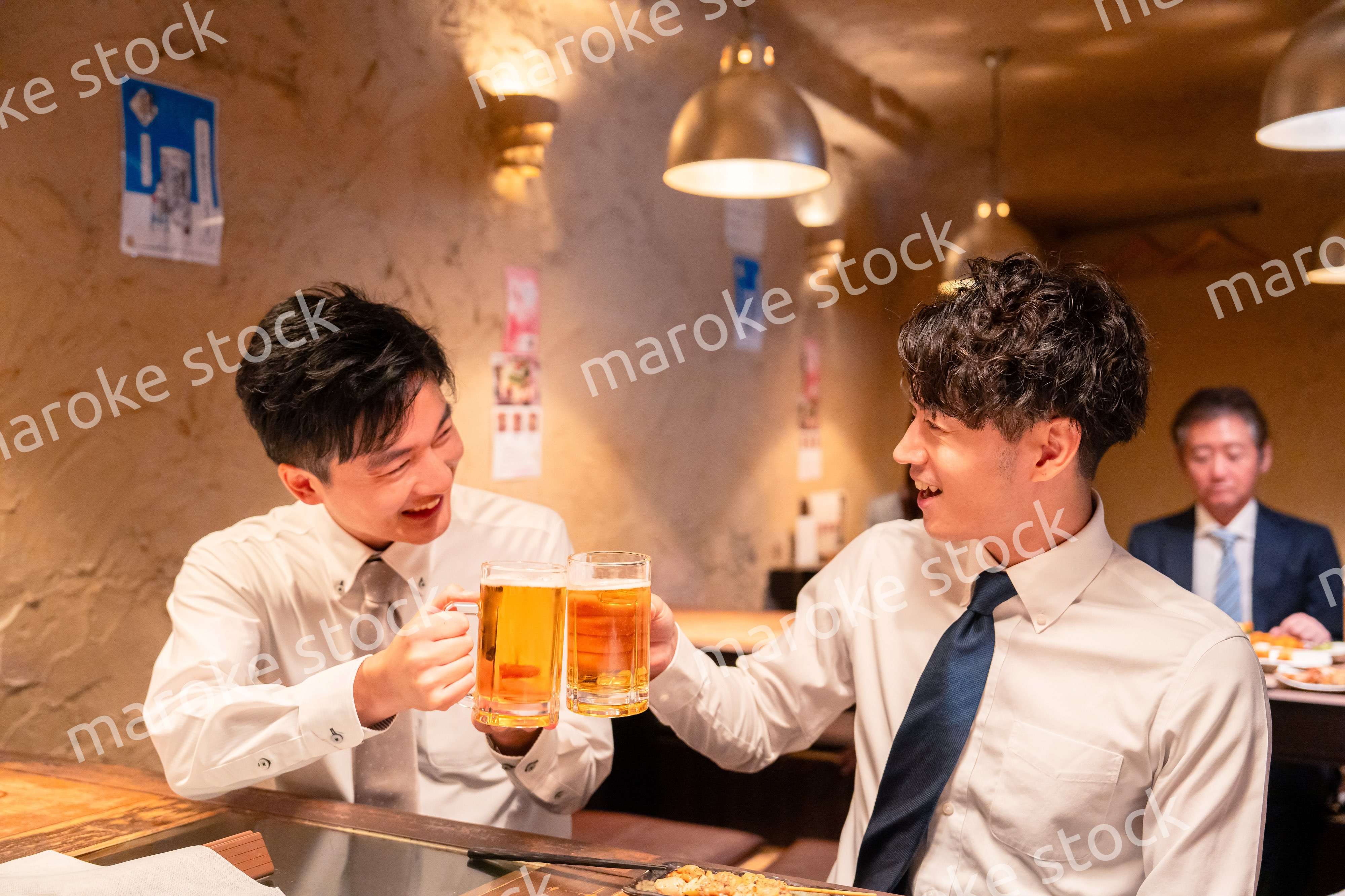 居酒屋でビールを飲む二人の若手ビジネスマン