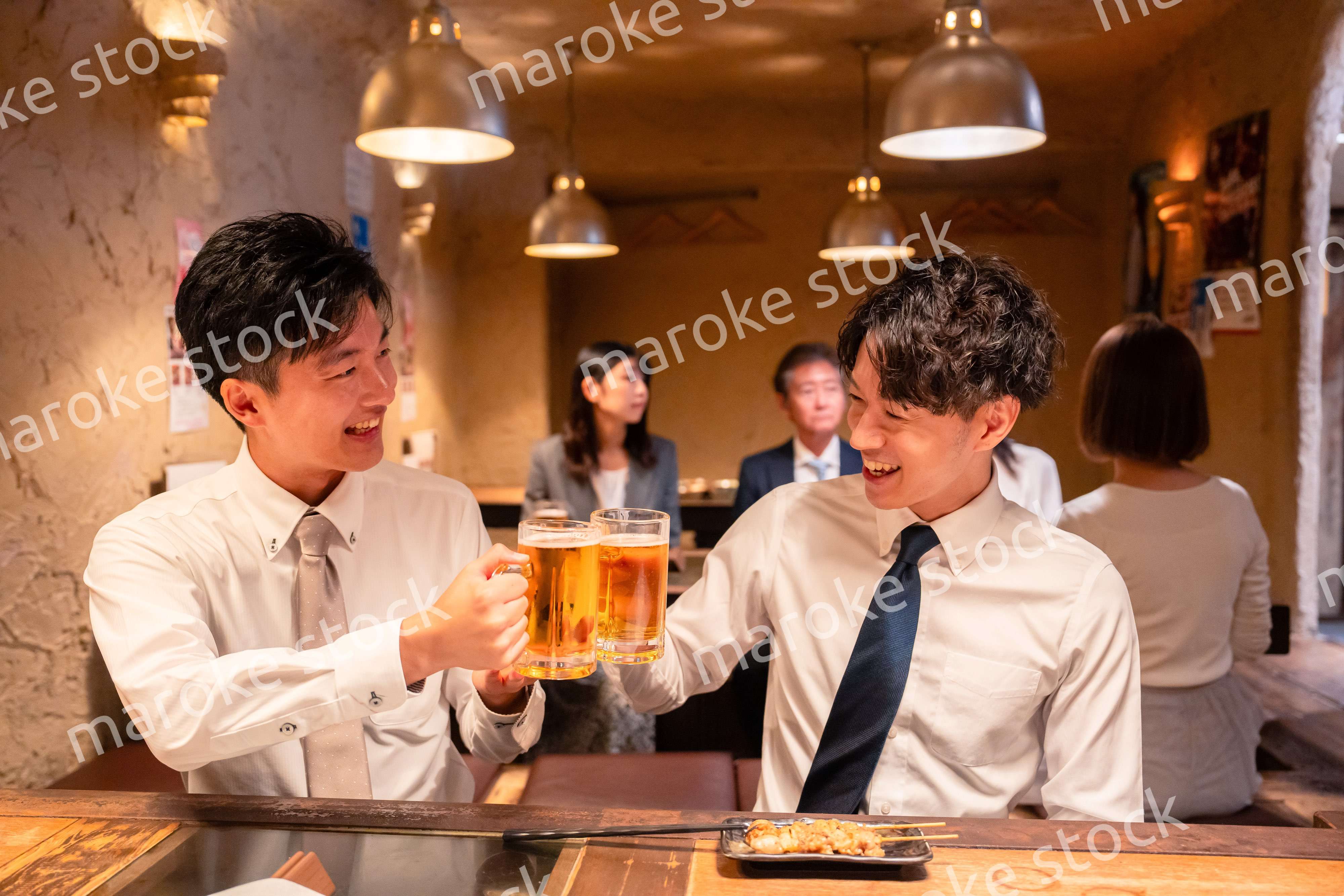 居酒屋でビールを飲む二人の若手ビジネスマン