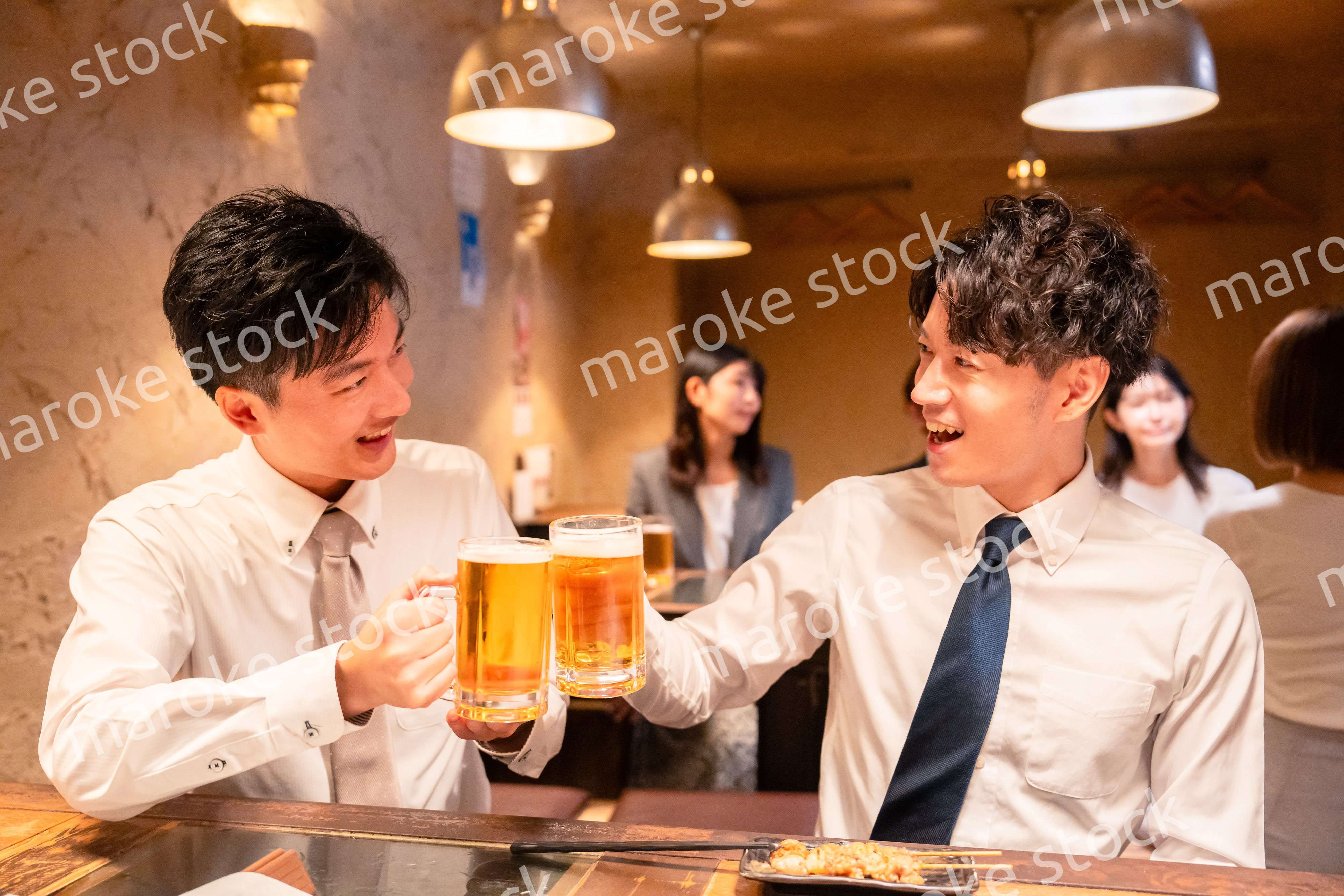 居酒屋でビールを飲む二人の若手ビジネスマン