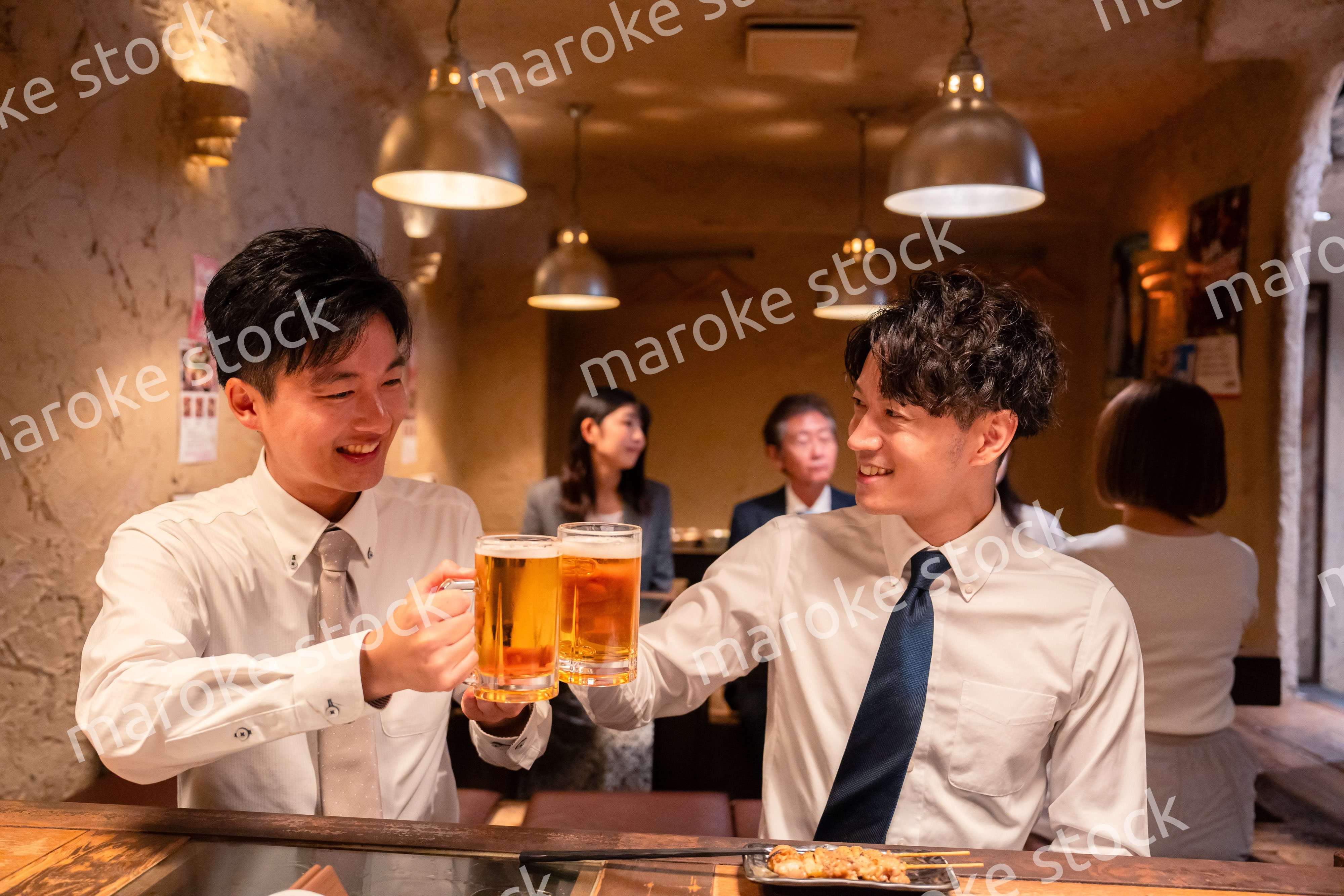 居酒屋でビールを飲む二人の若手ビジネスマン