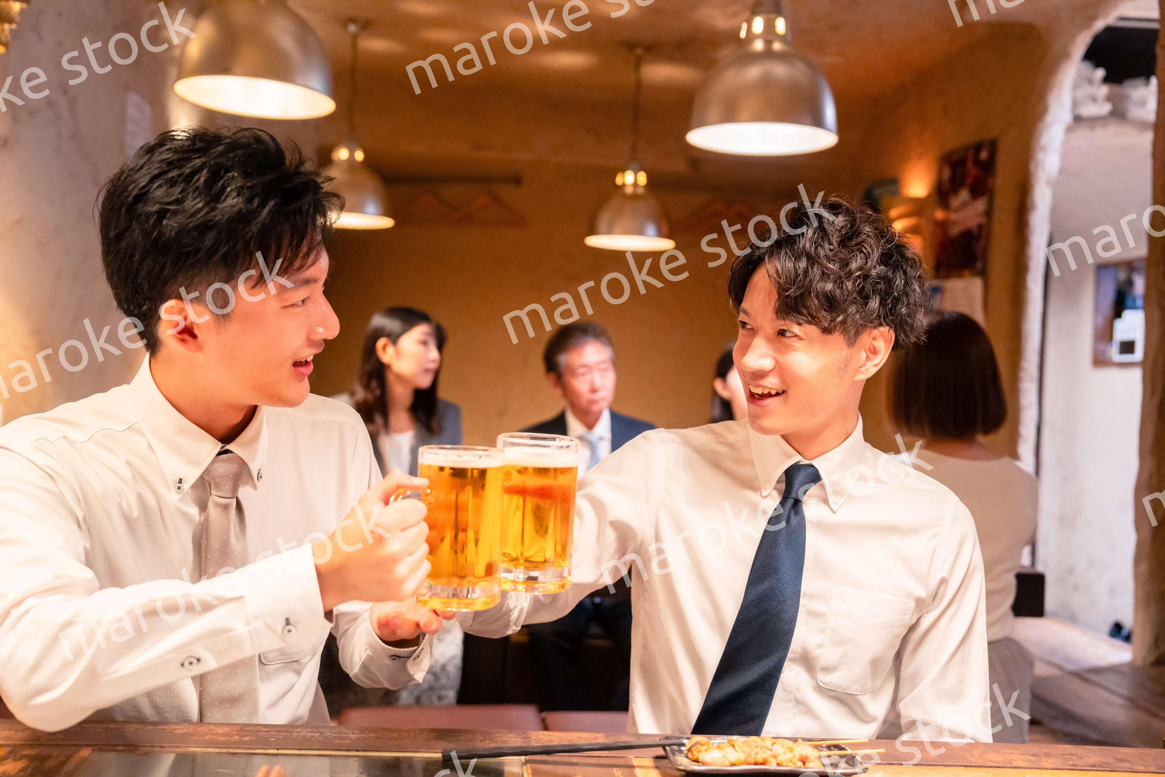 居酒屋でビールを飲む二人の若手ビジネスマン