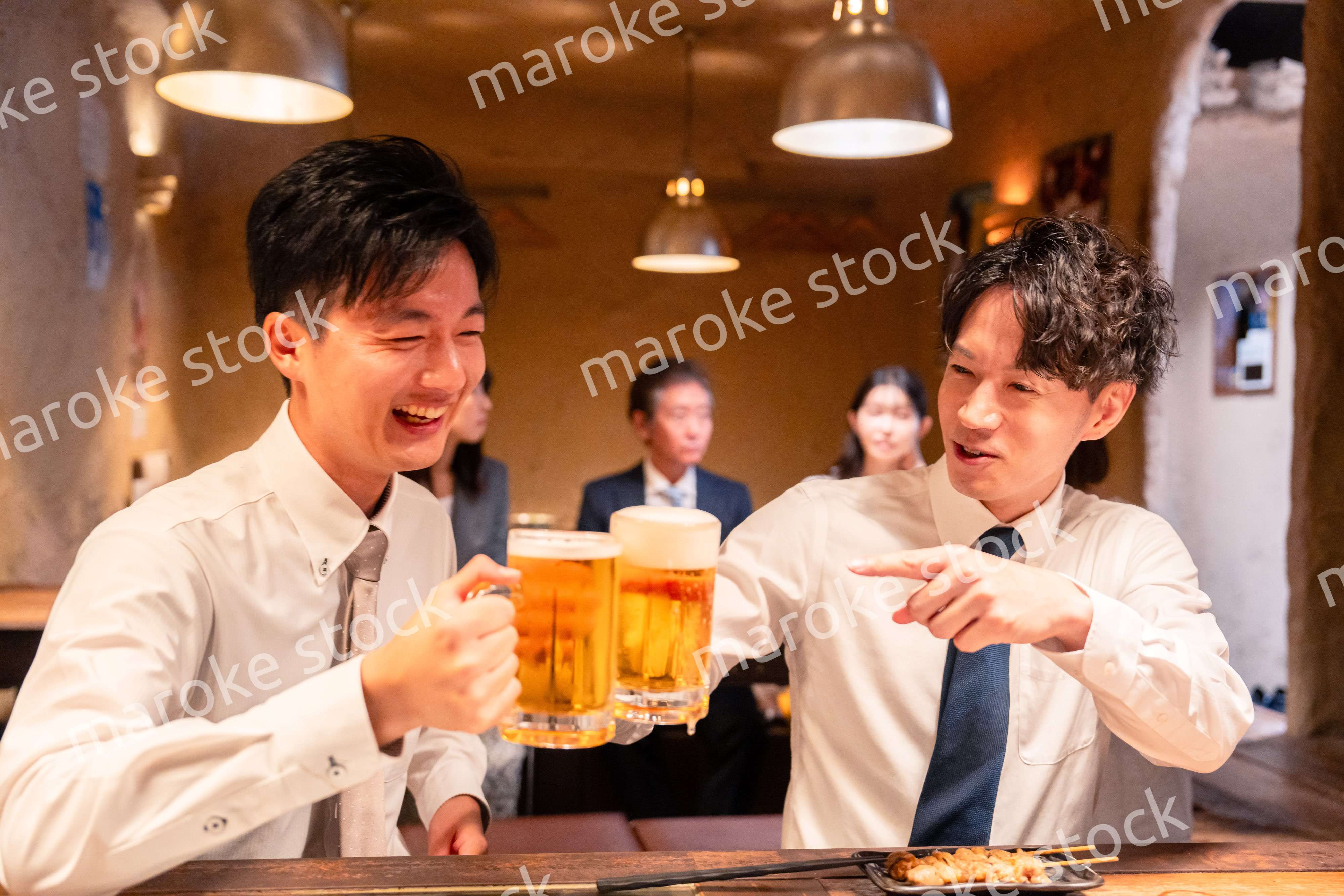 居酒屋でビールを飲む二人の若手ビジネスマン