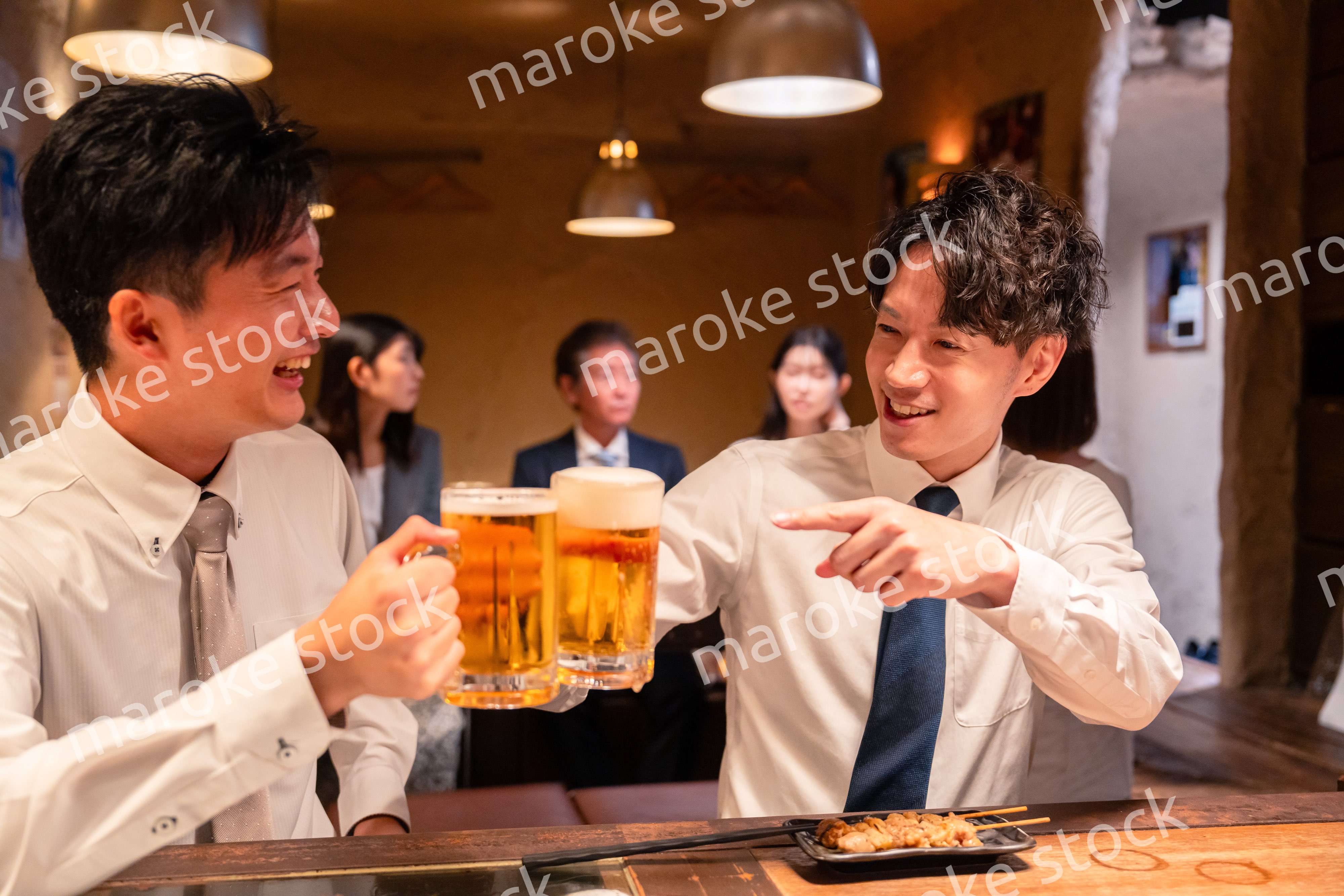 居酒屋でビールを飲む二人の若手ビジネスマン