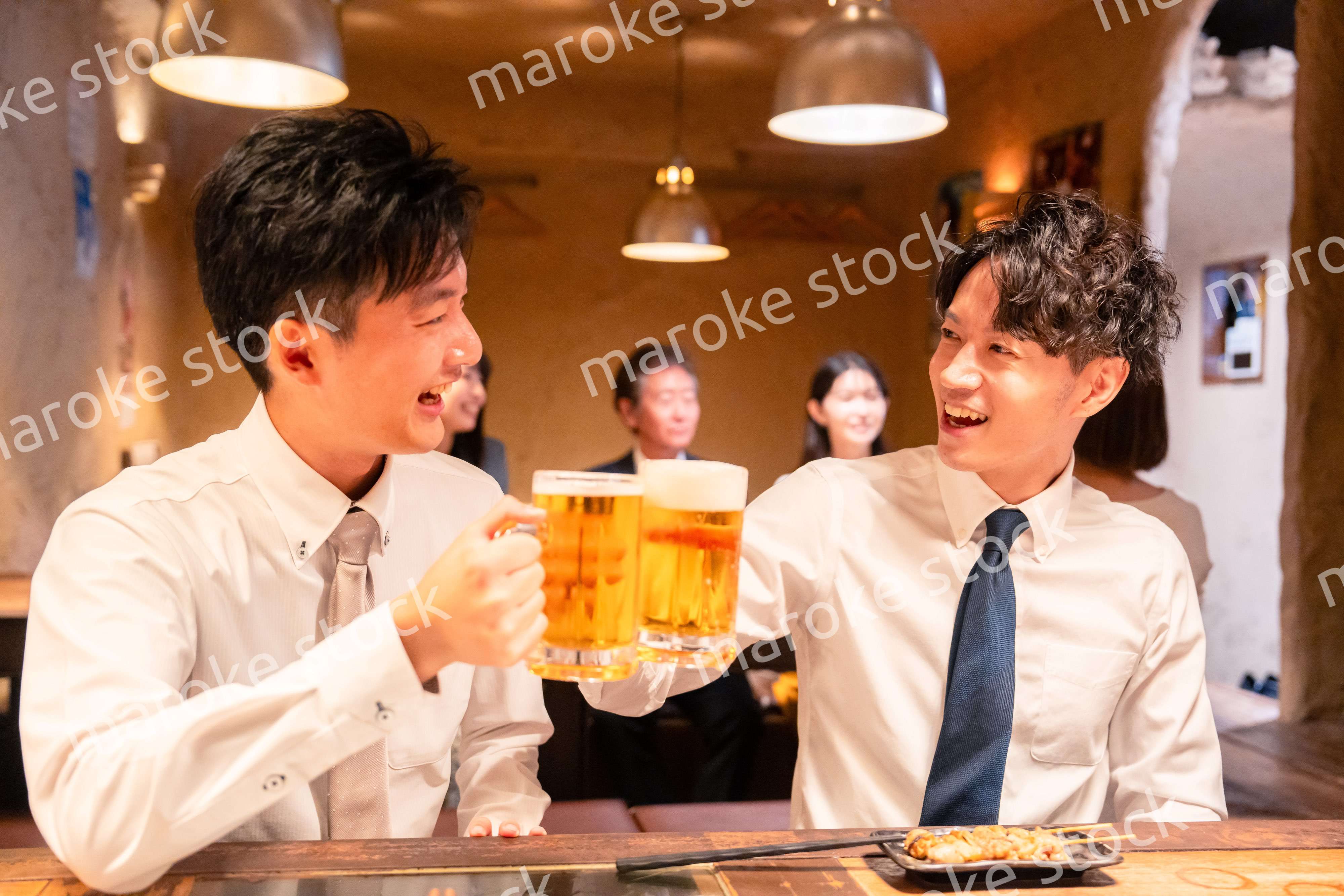 居酒屋でビールを飲む二人の若手ビジネスマン