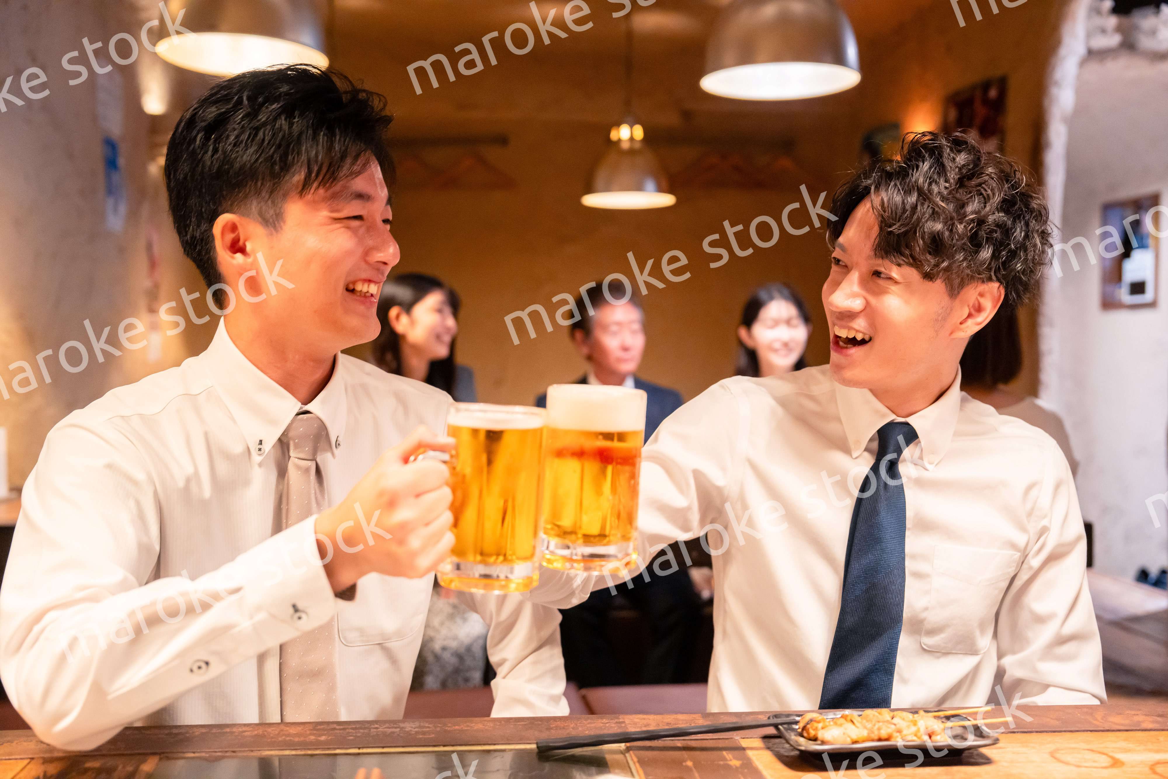居酒屋でビールを飲む二人の若手ビジネスマン