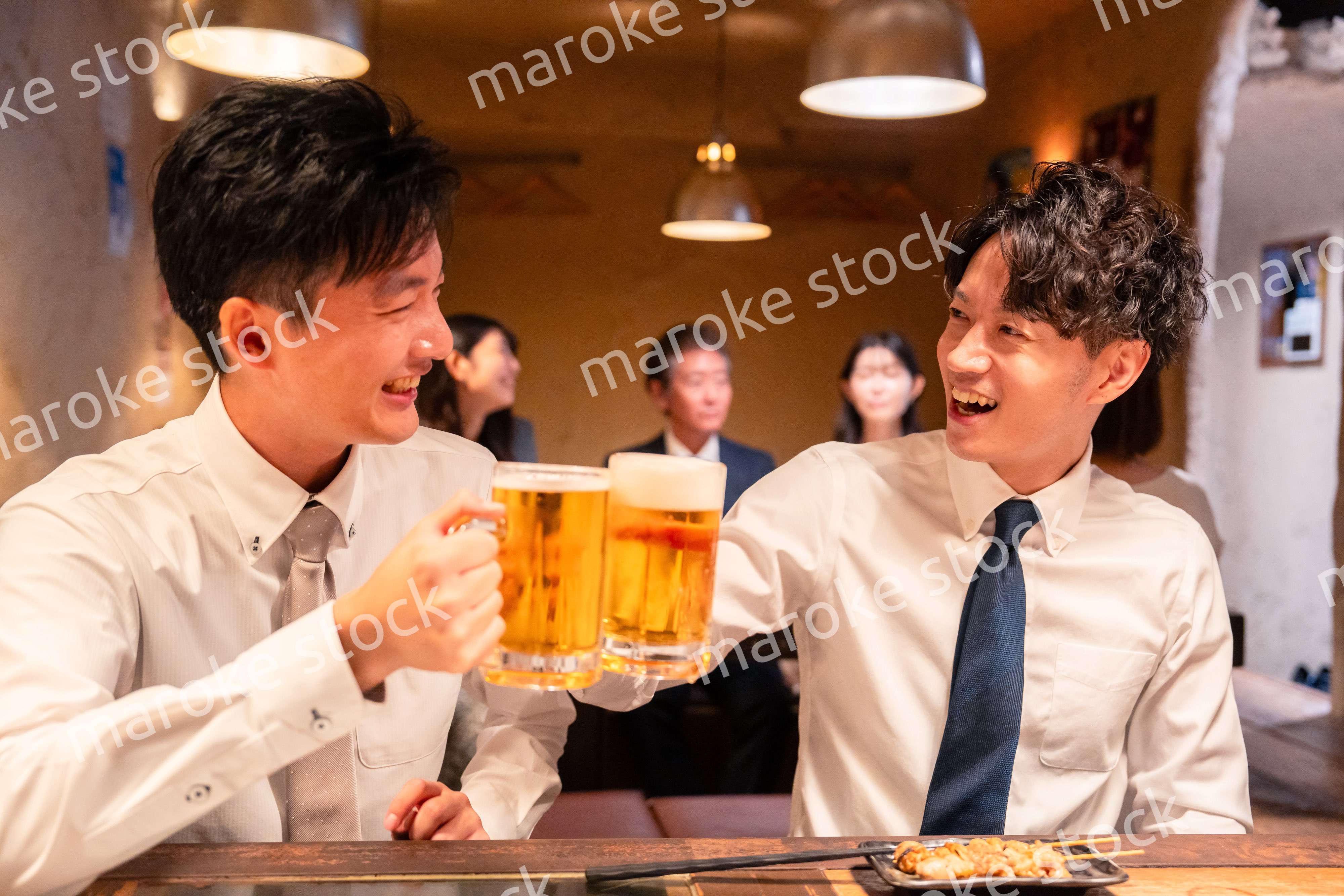 居酒屋でビールを飲む二人の若手ビジネスマン