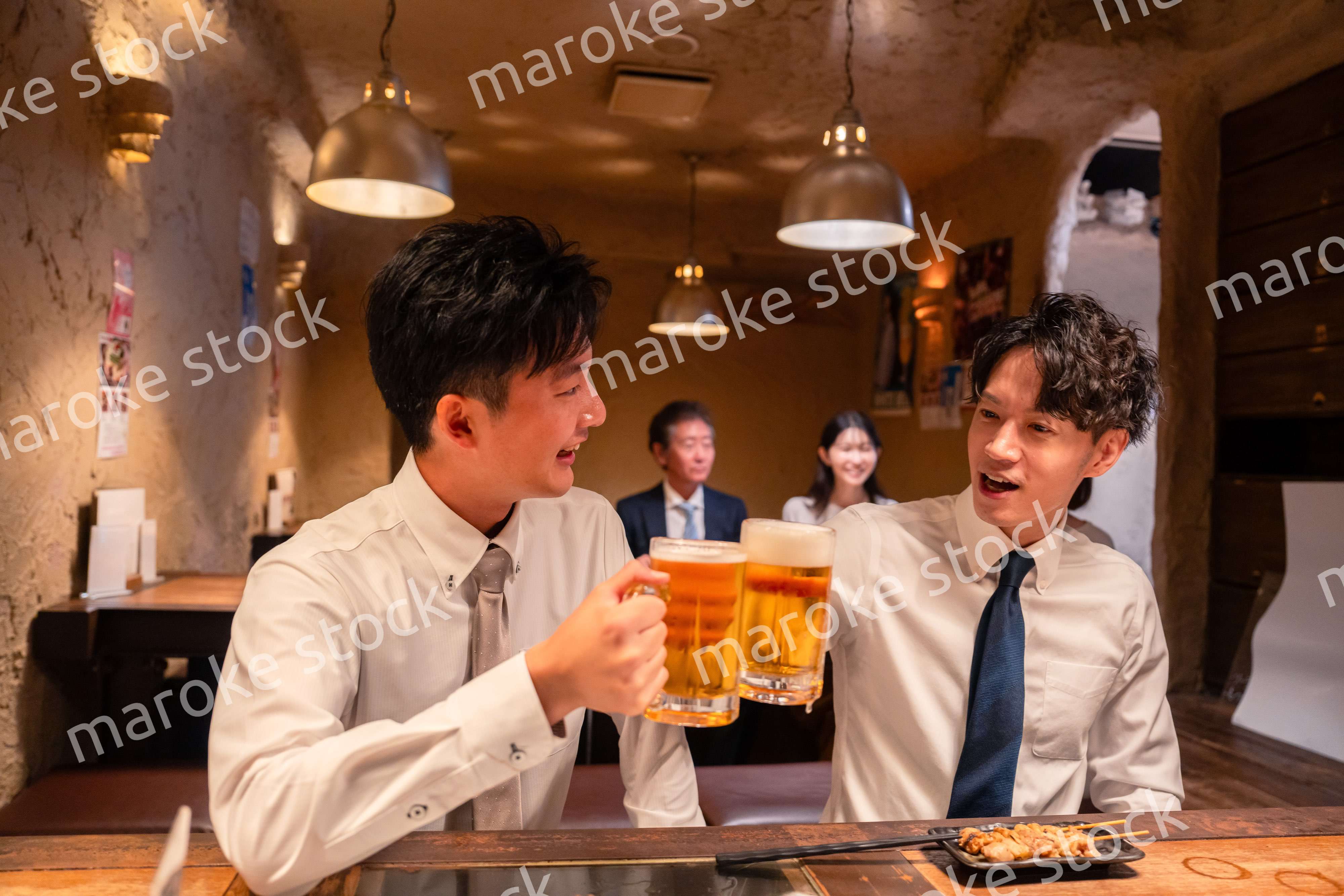 居酒屋でビールを飲む二人の若手ビジネスマン