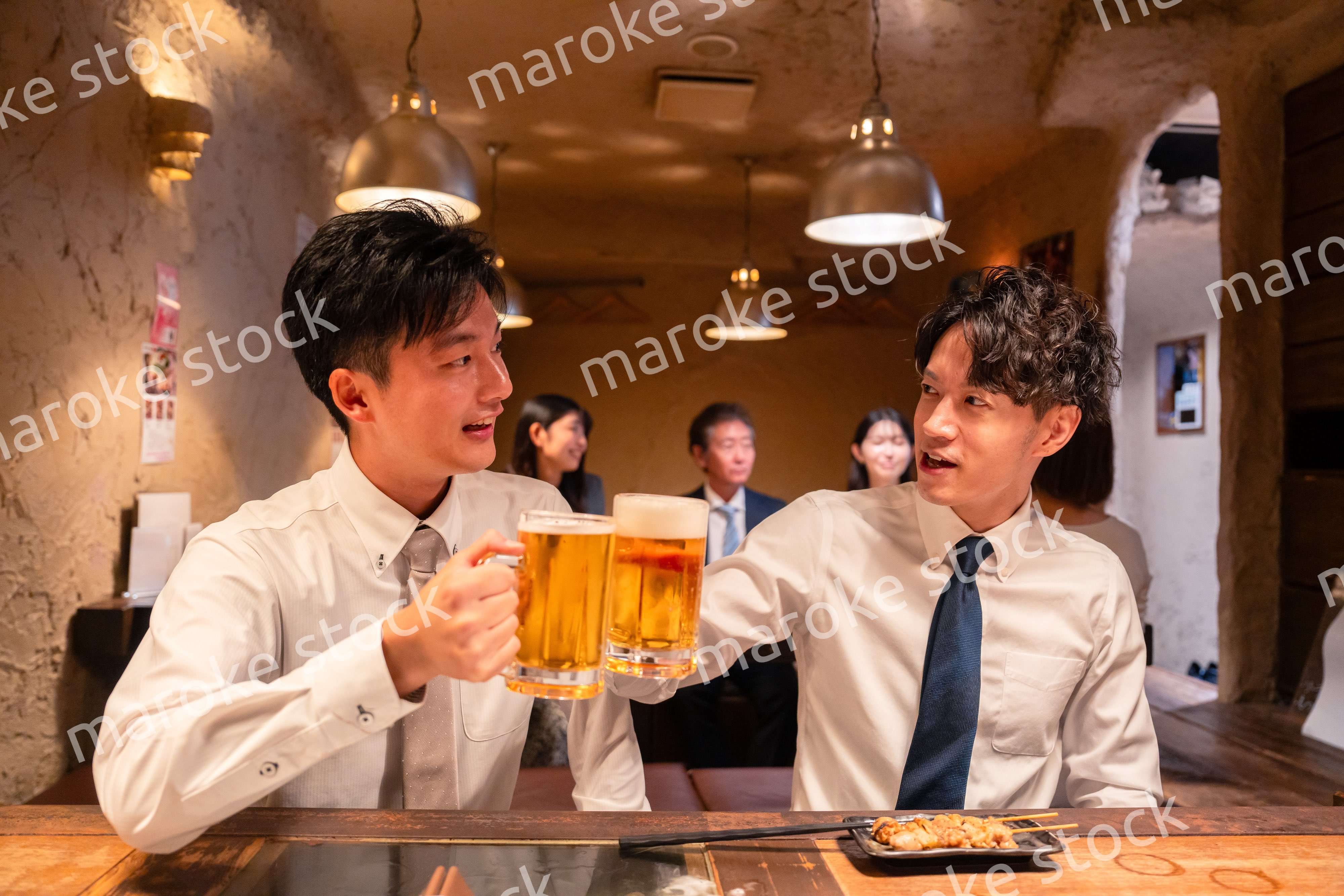 居酒屋でビールを飲む二人の若手ビジネスマン