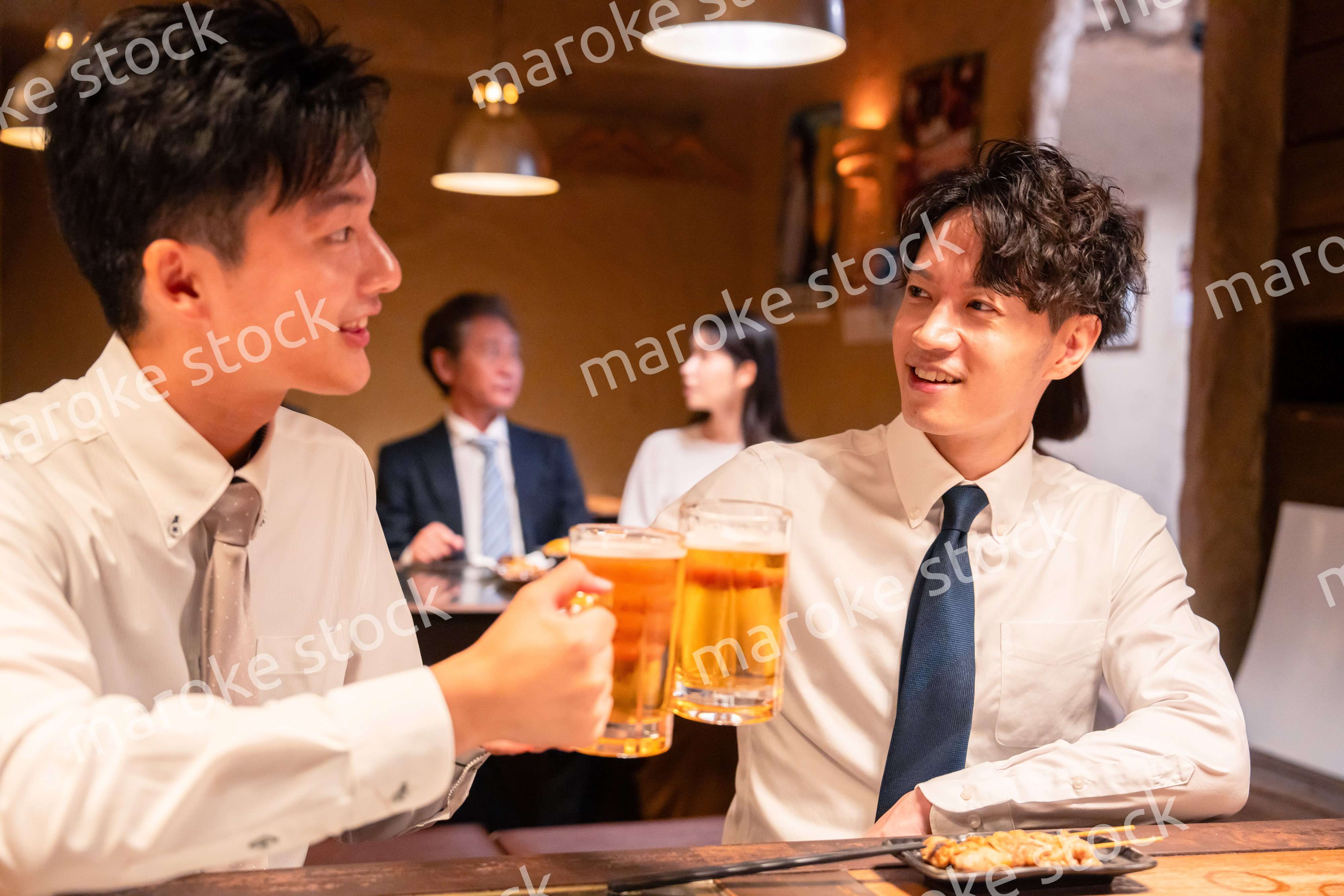 居酒屋でビールを飲む二人の若手ビジネスマン