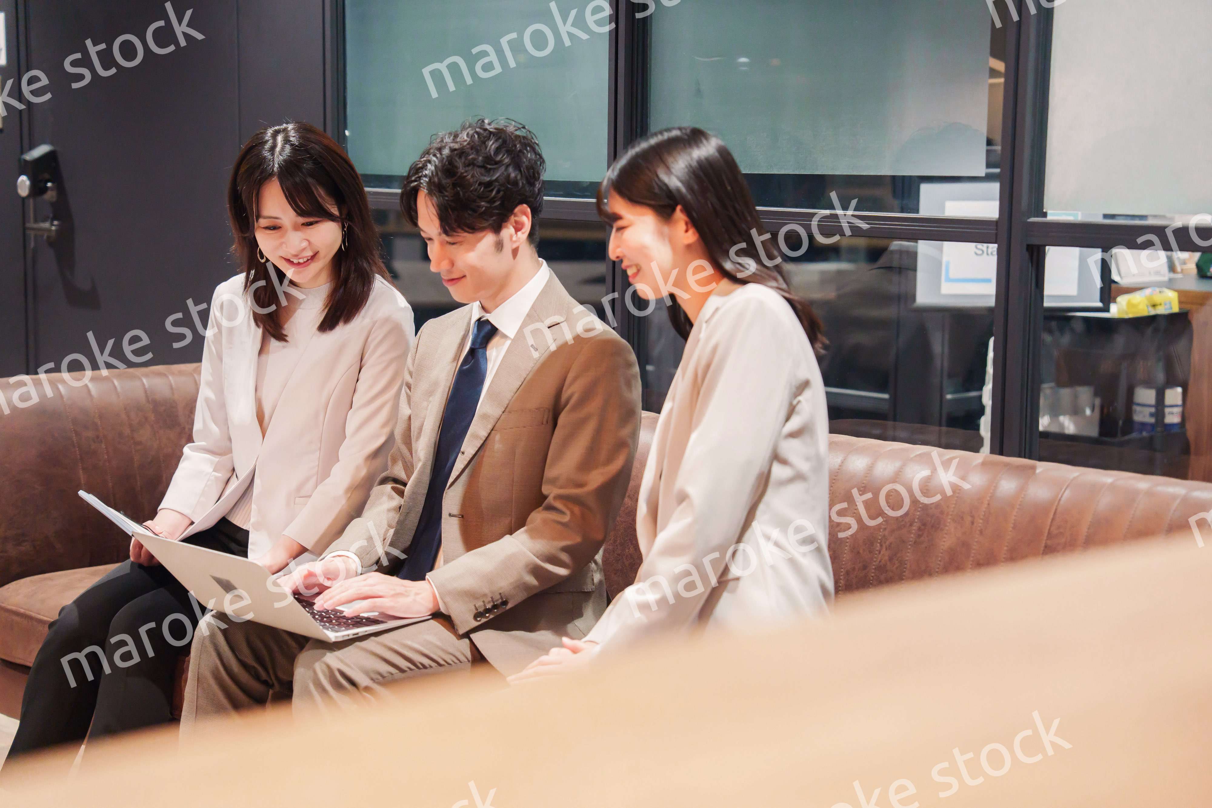 オフィスのソファーでカジュアルに打ち合わせをするビジネスパーソン