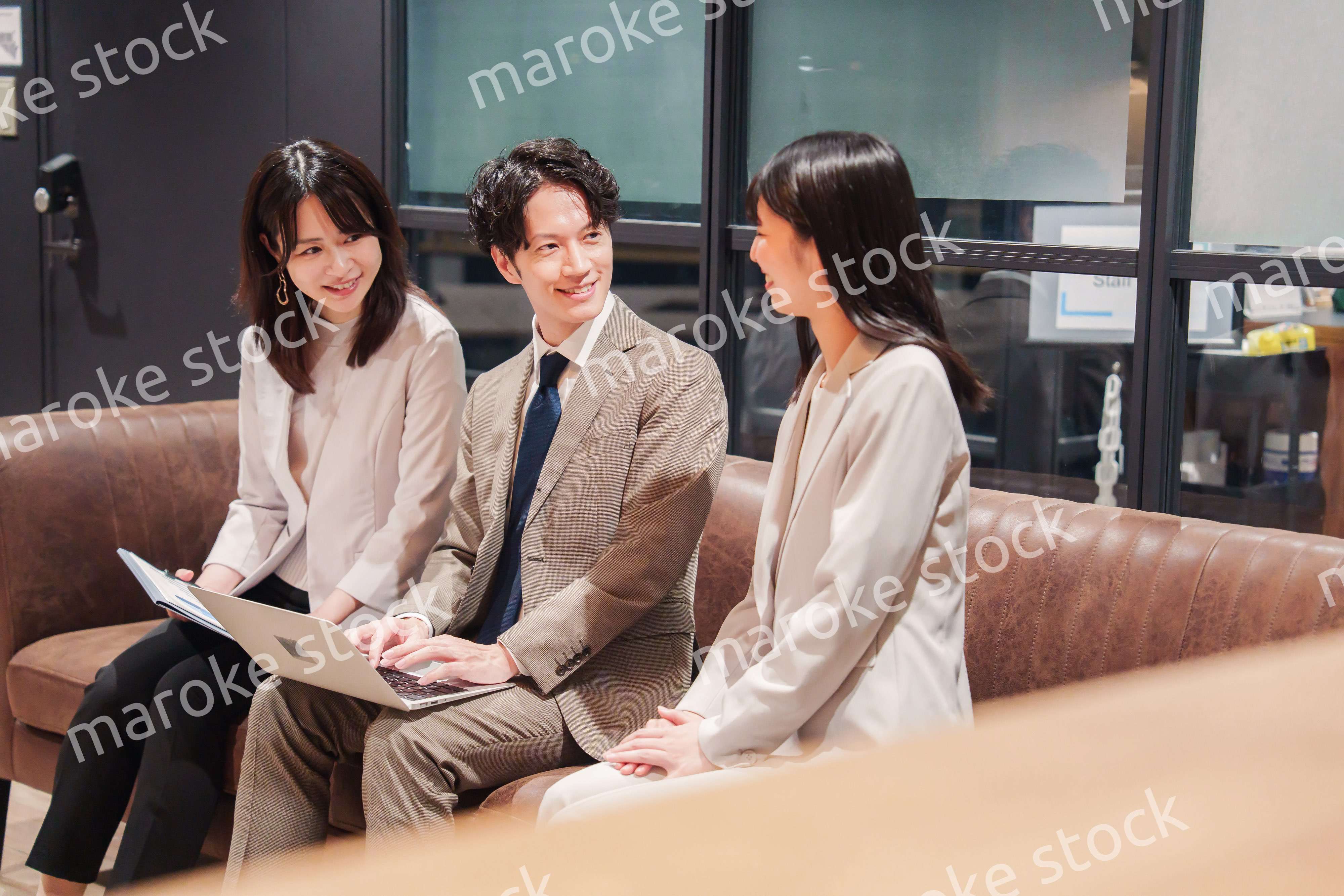 オフィスのソファーでカジュアルに打ち合わせをするビジネスパーソン