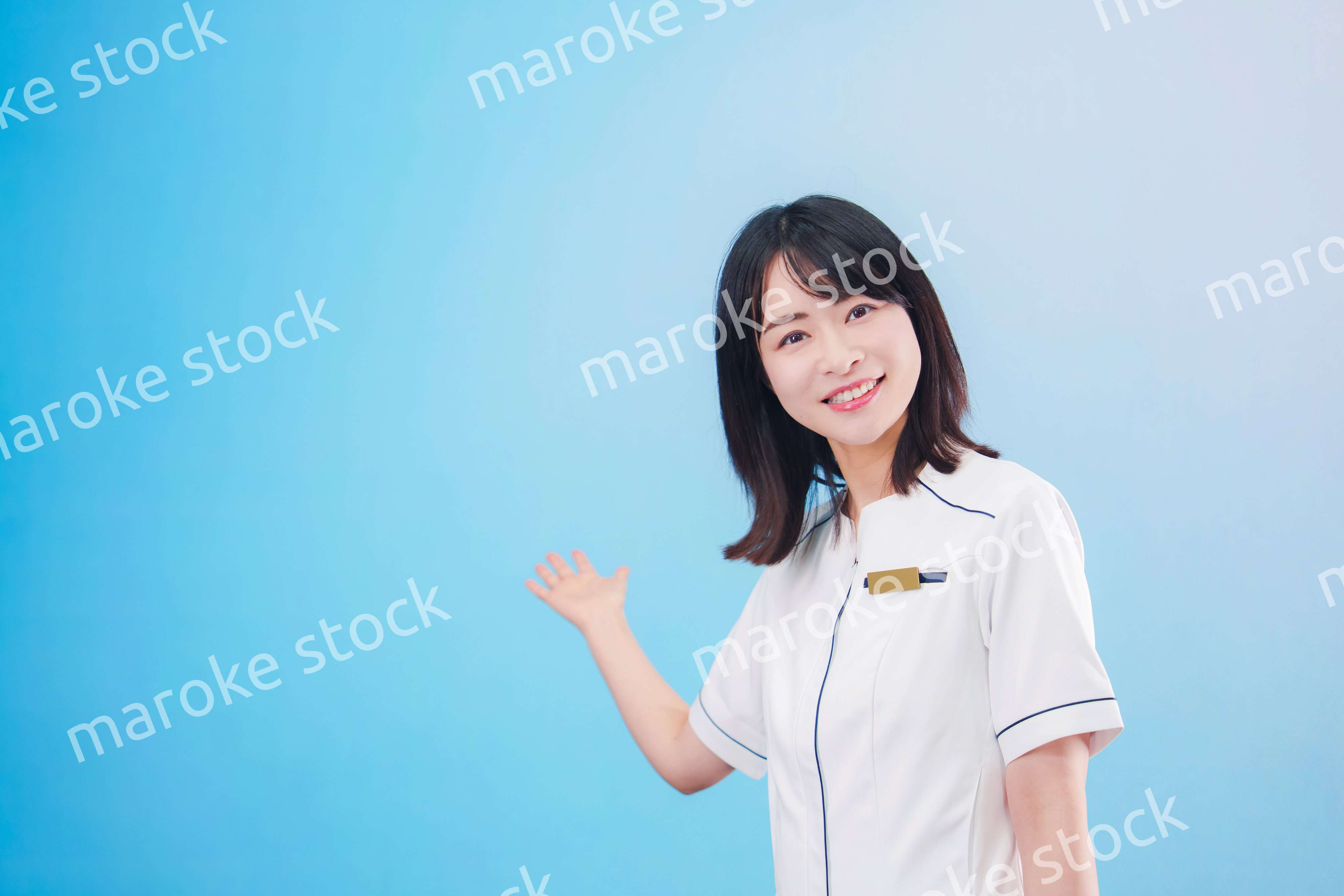 クリニックの受付をする若い女性スタッフ（水色背景）