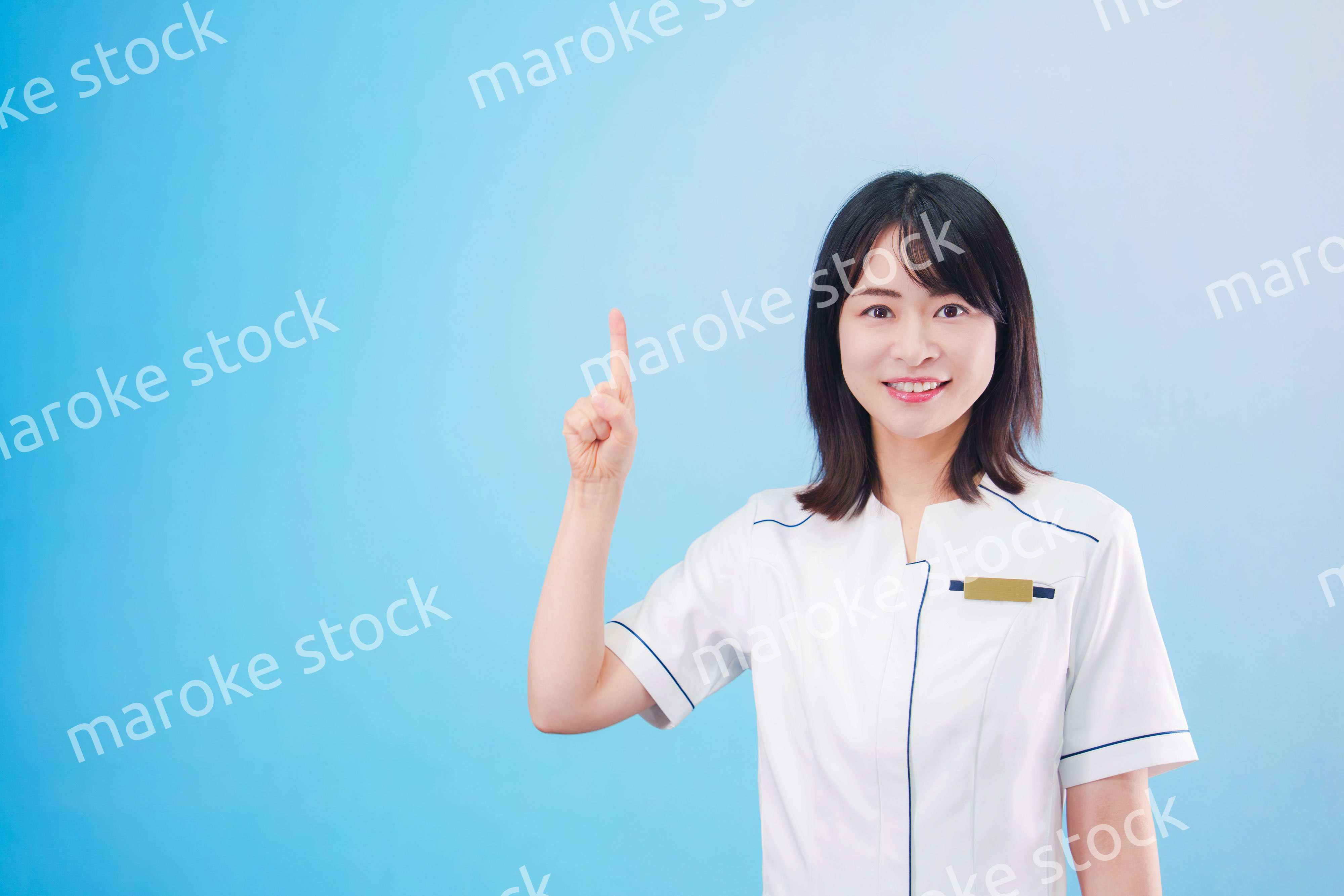 クリニックの受付をする若い女性スタッフ（水色背景）