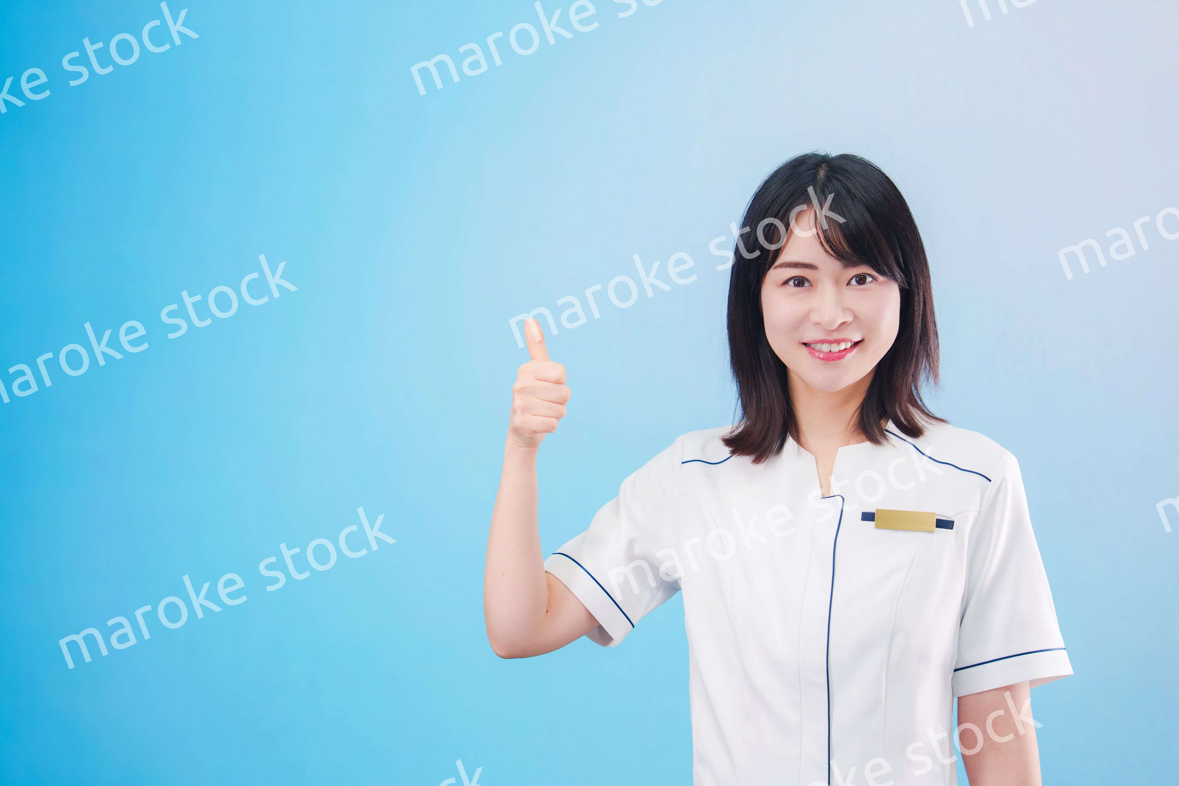 クリニックの受付をする若い女性スタッフ（水色背景）