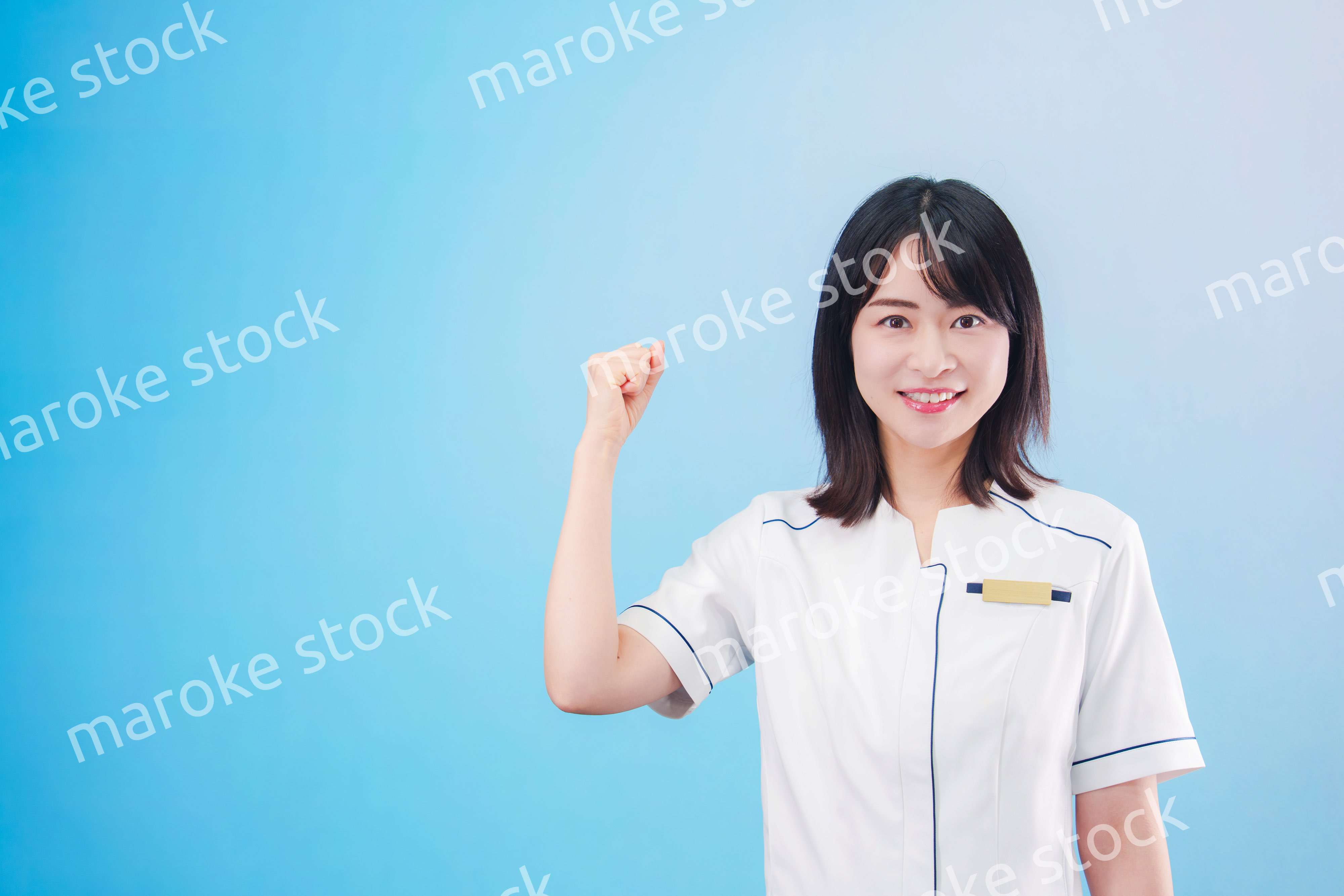 クリニックの受付をする若い女性スタッフ（水色背景）