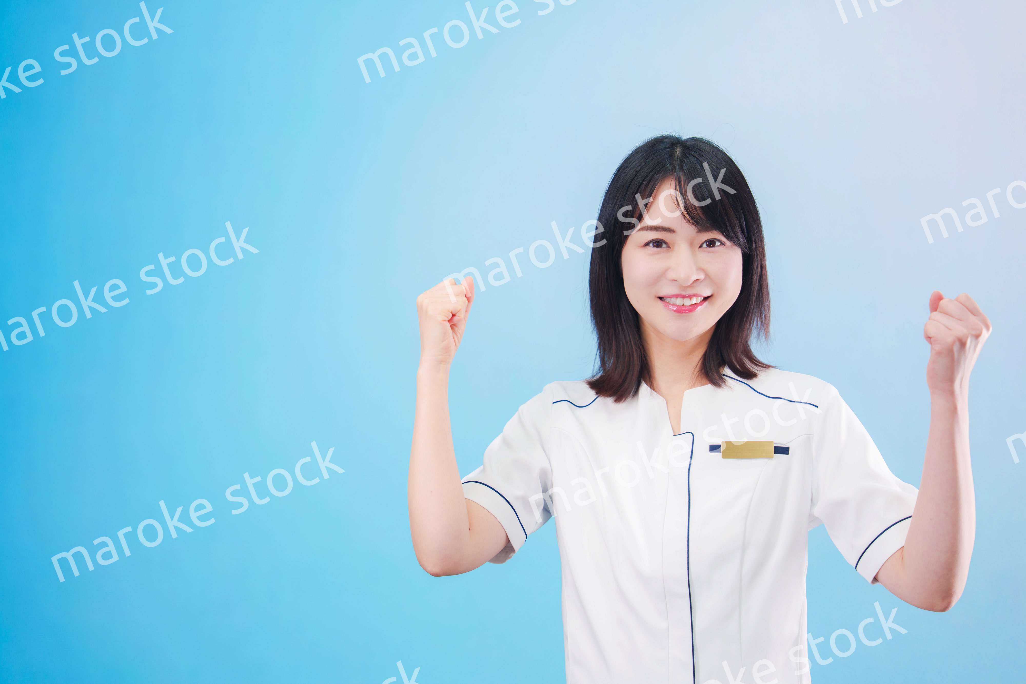 クリニックの受付をする若い女性スタッフ（水色背景）