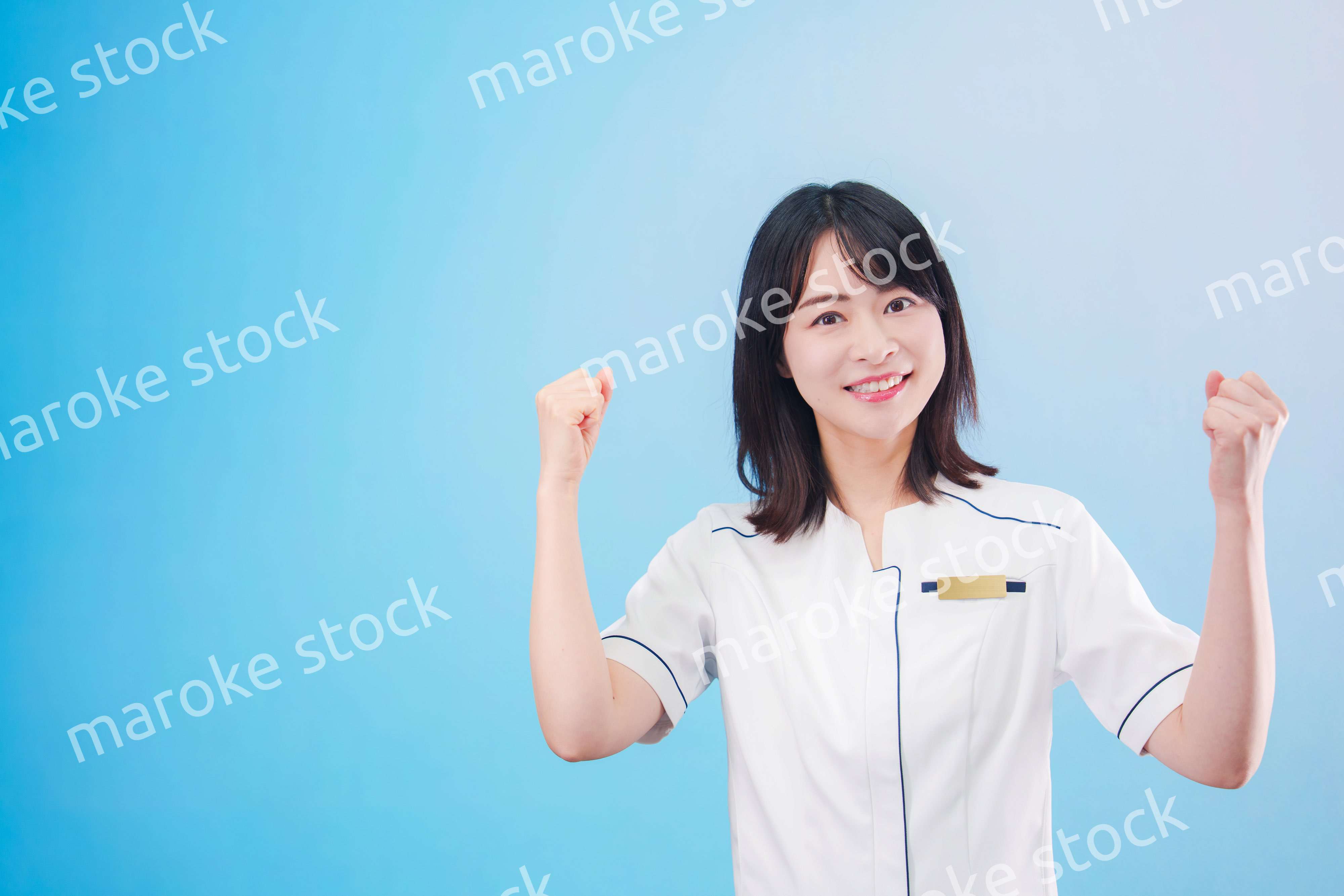 クリニックの受付をする若い女性スタッフ（水色背景）