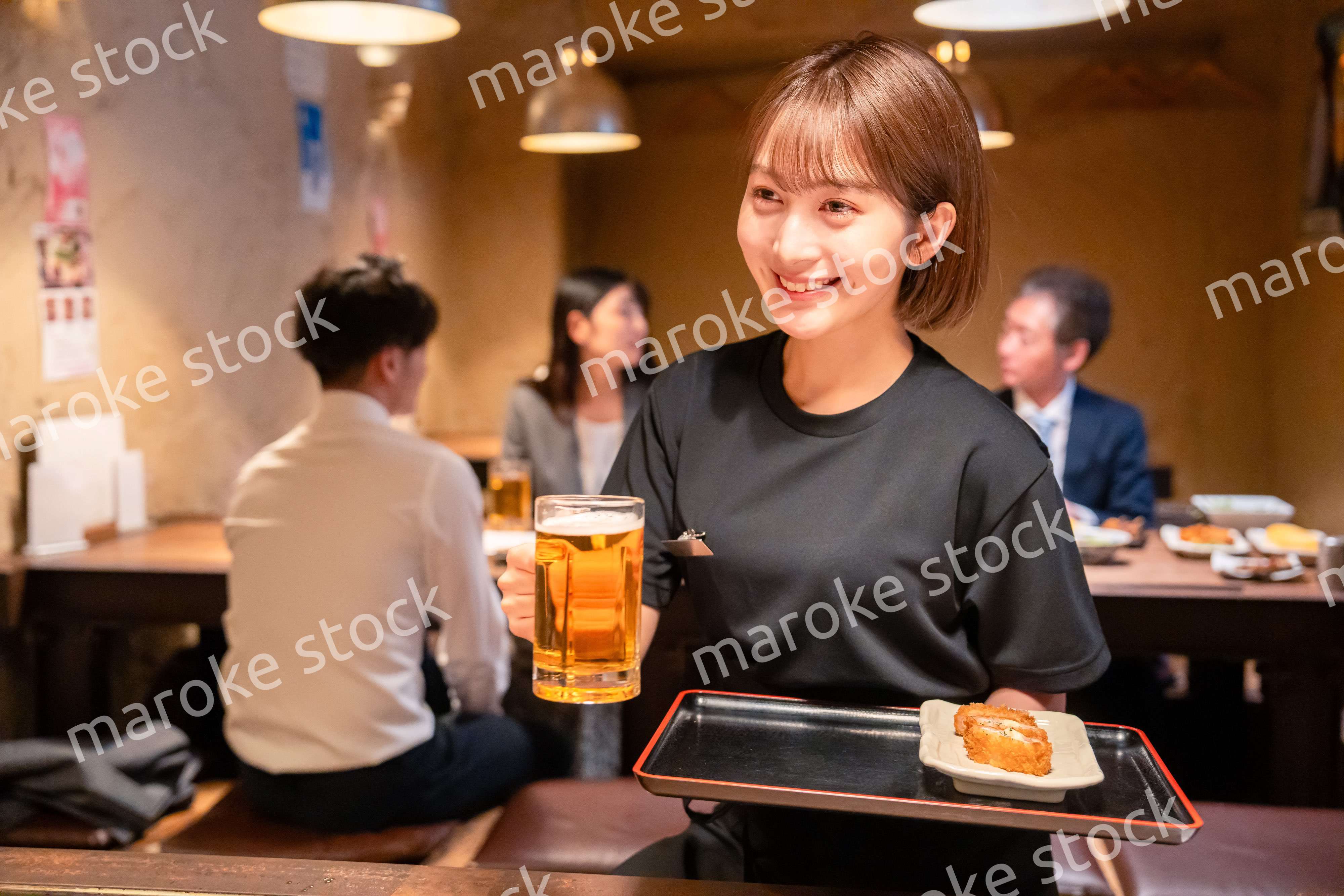 ビールを提供する居酒屋の女性スタッフ