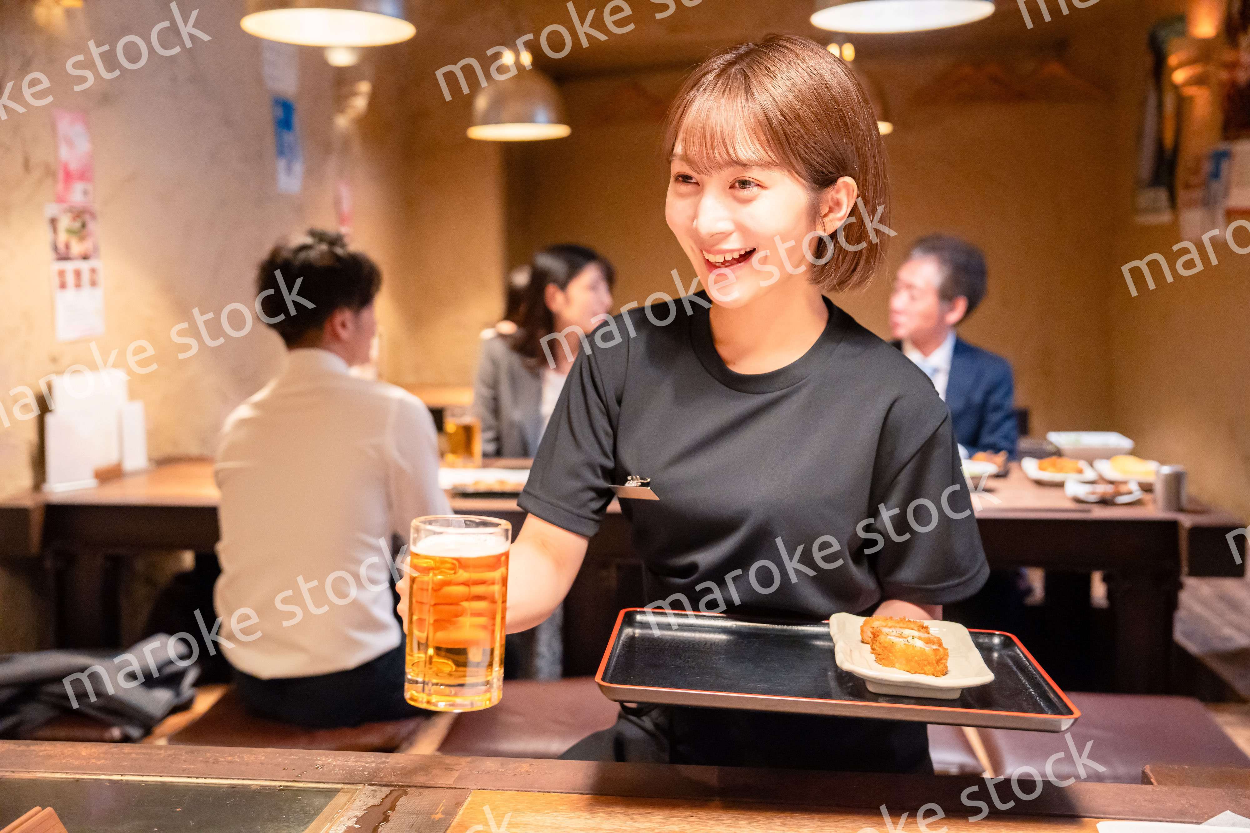 ビールを提供する居酒屋の女性スタッフ