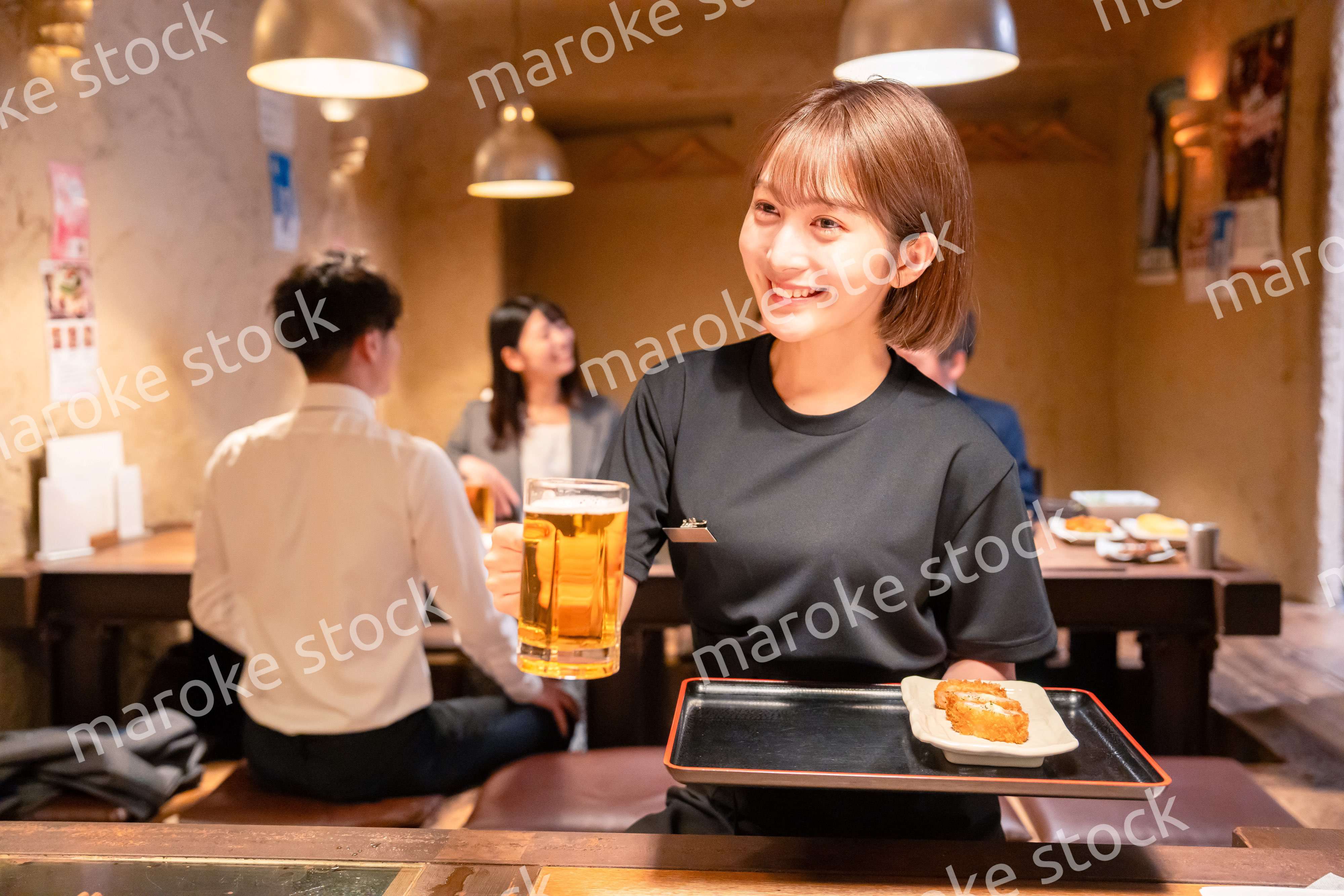 ビールを提供する居酒屋の女性スタッフ