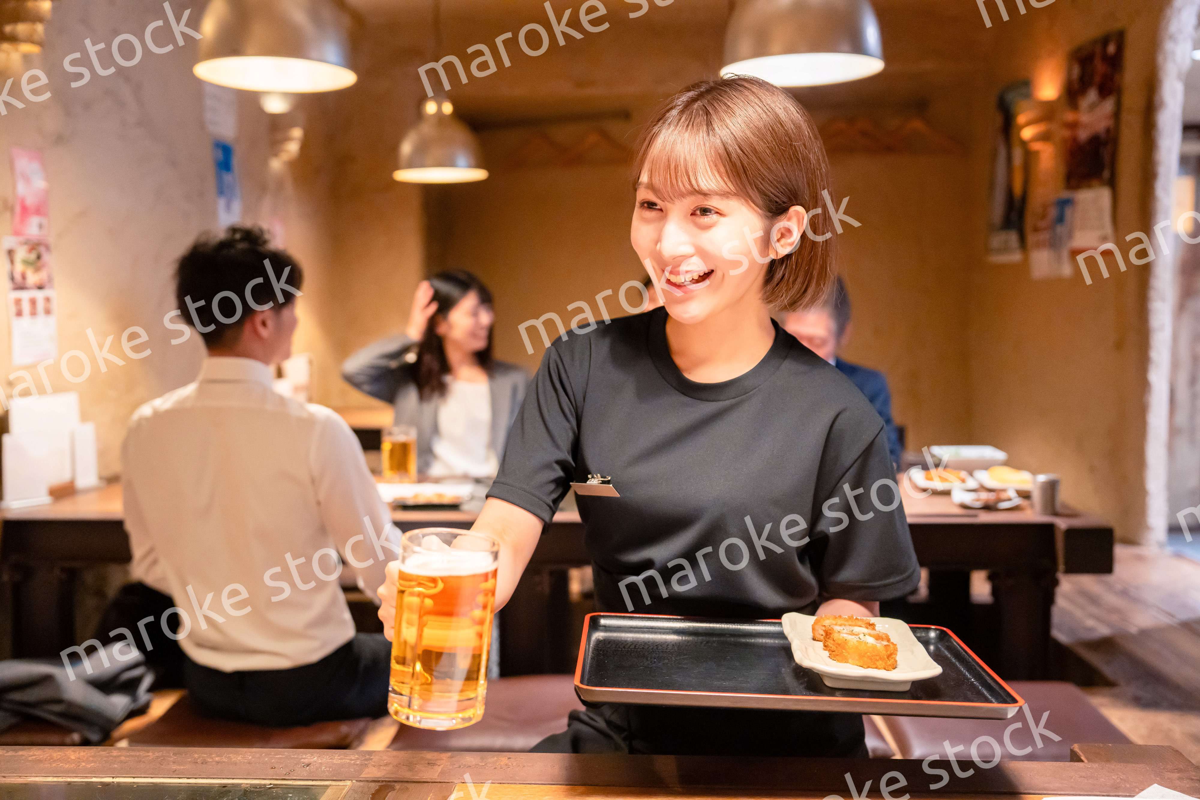 ビールを提供する居酒屋の女性スタッフ