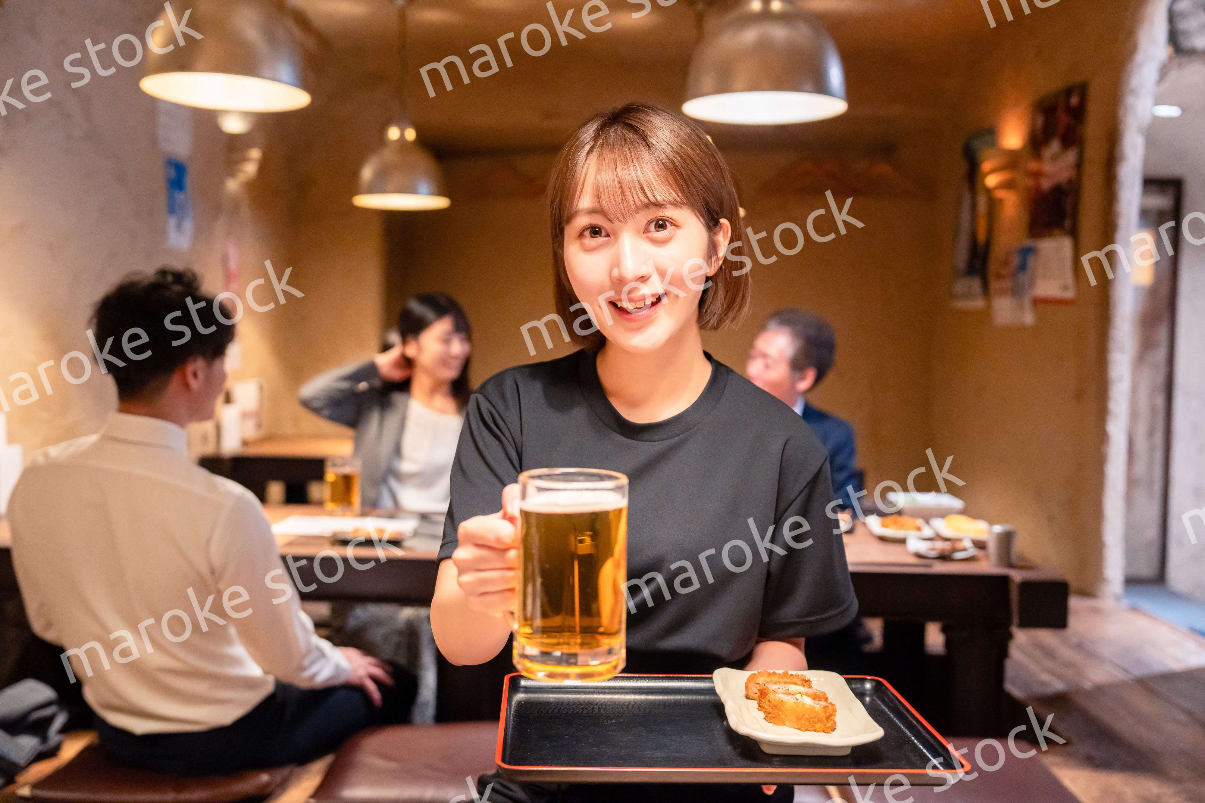ビールを提供する居酒屋の女性スタッフ