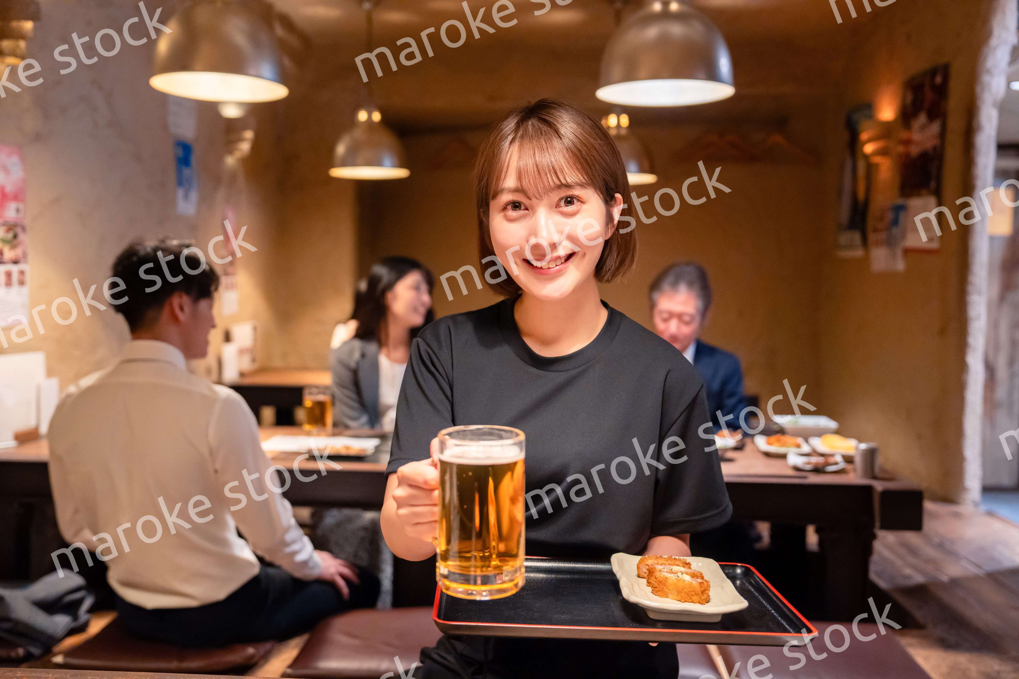 ビールを提供する居酒屋の女性スタッフ
