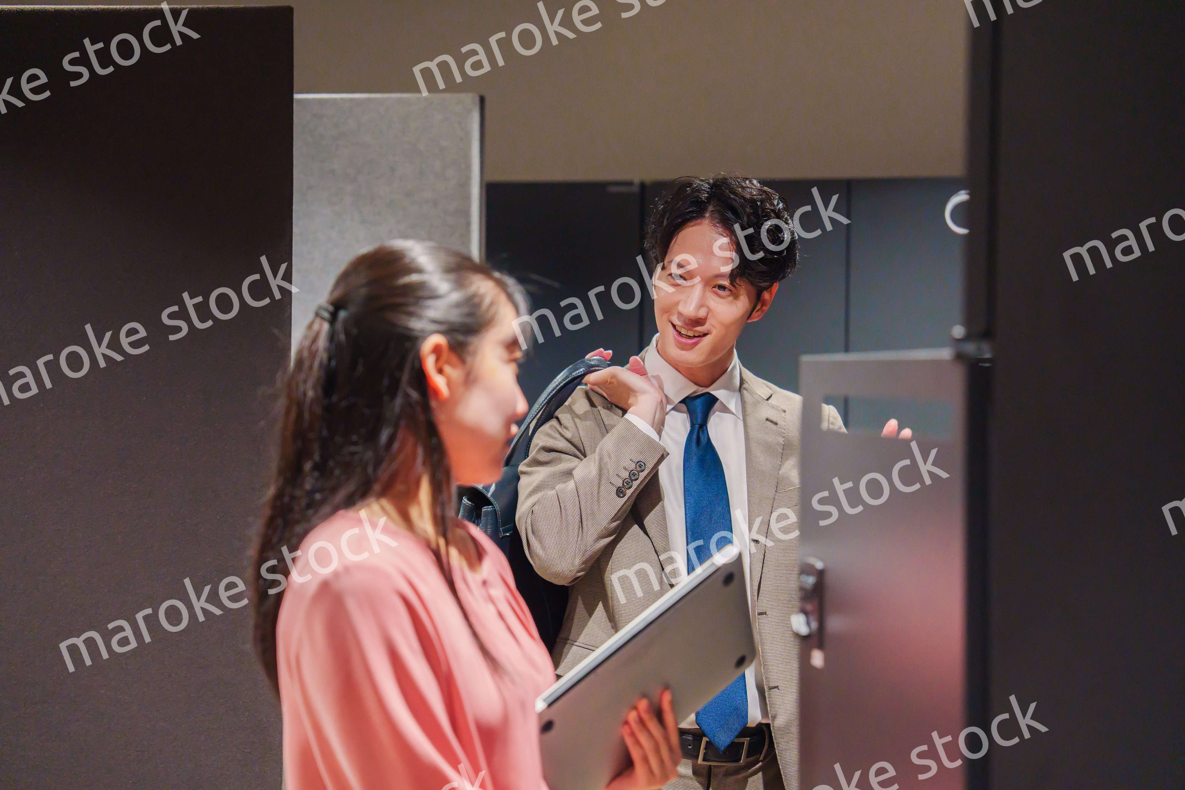 オフィスのロッカーで会話をする男女の会社員