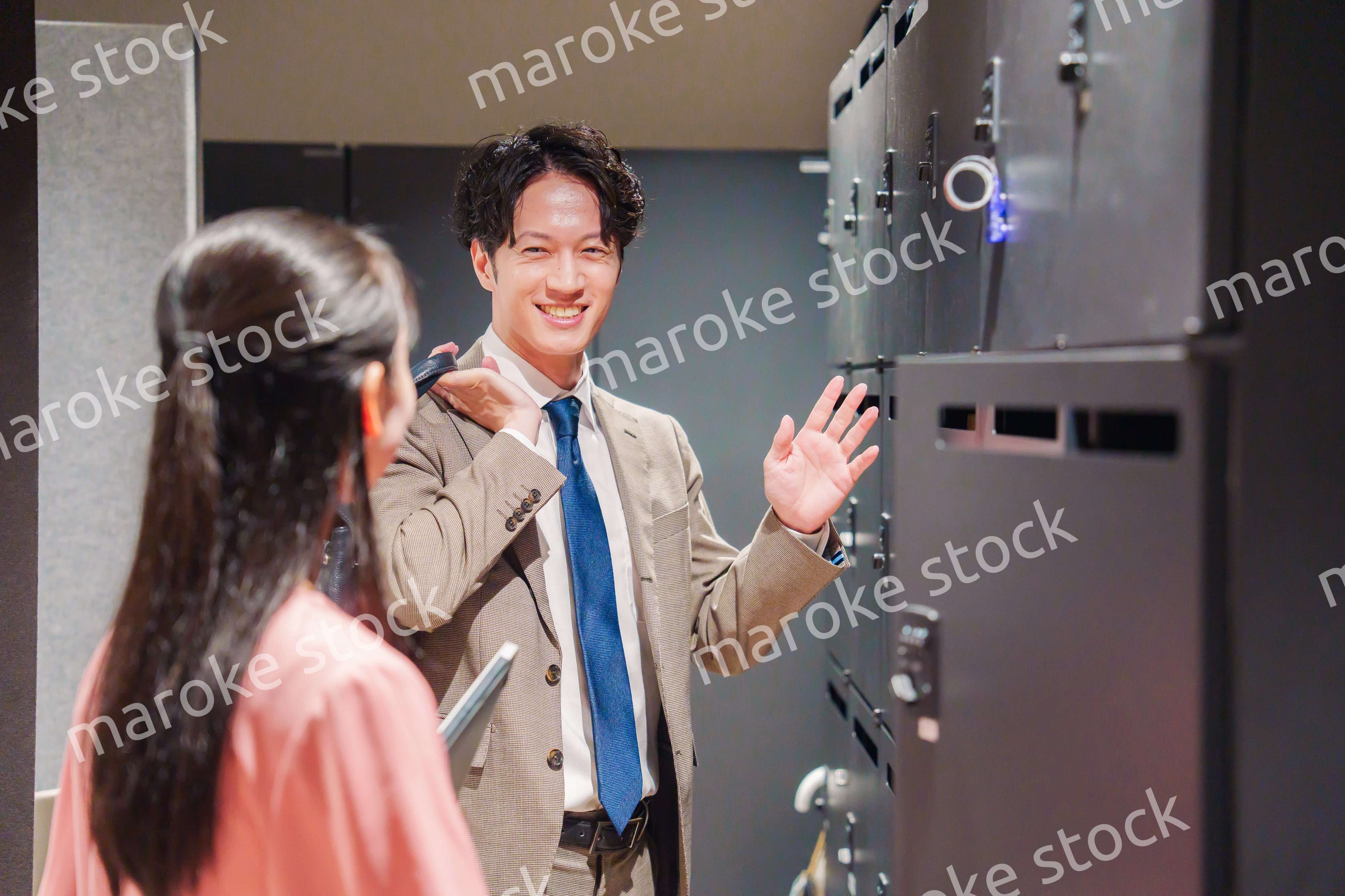 オフィスのロッカーで会話をする男女の会社員